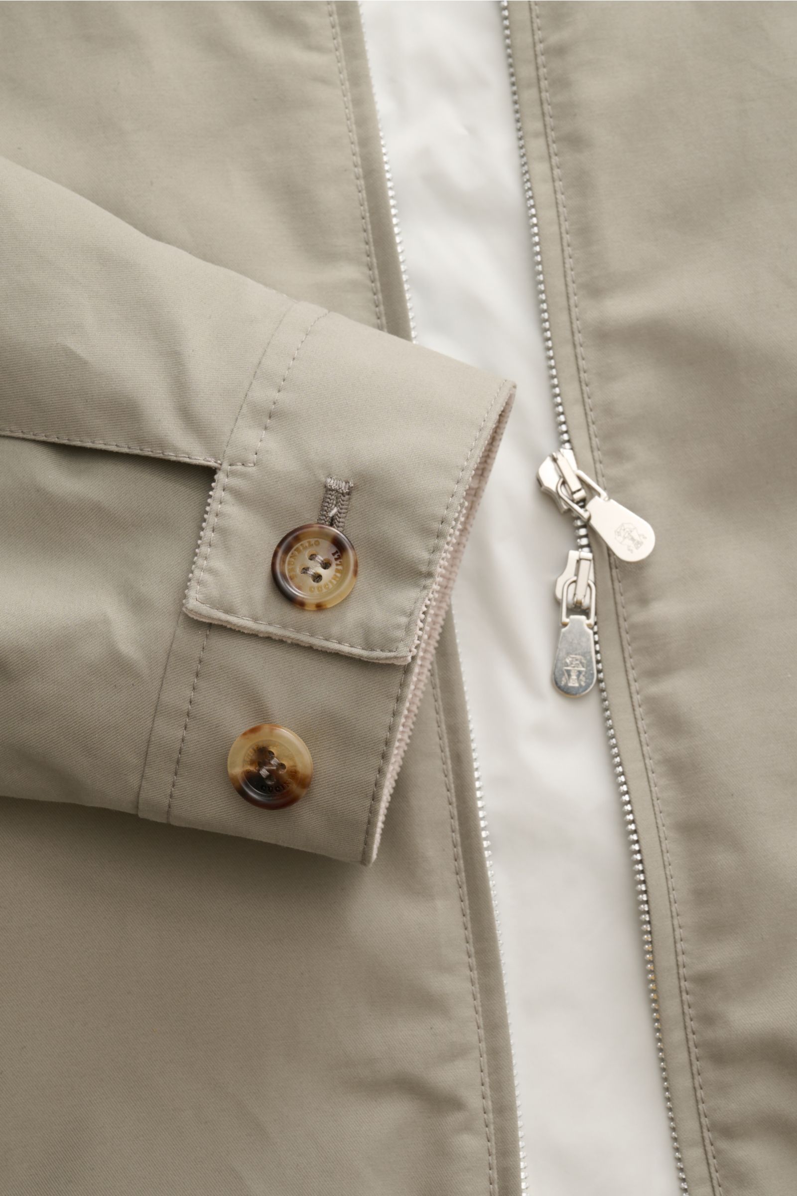 Close-up front view of the Brunello Cucinelli Blouson salbei in light beige, showing detailed buttons on the cuff and silver two-way zipper, highlighting the soft twill cotton-microfiber blend fabric with water-repellent and breathable features, fine cord