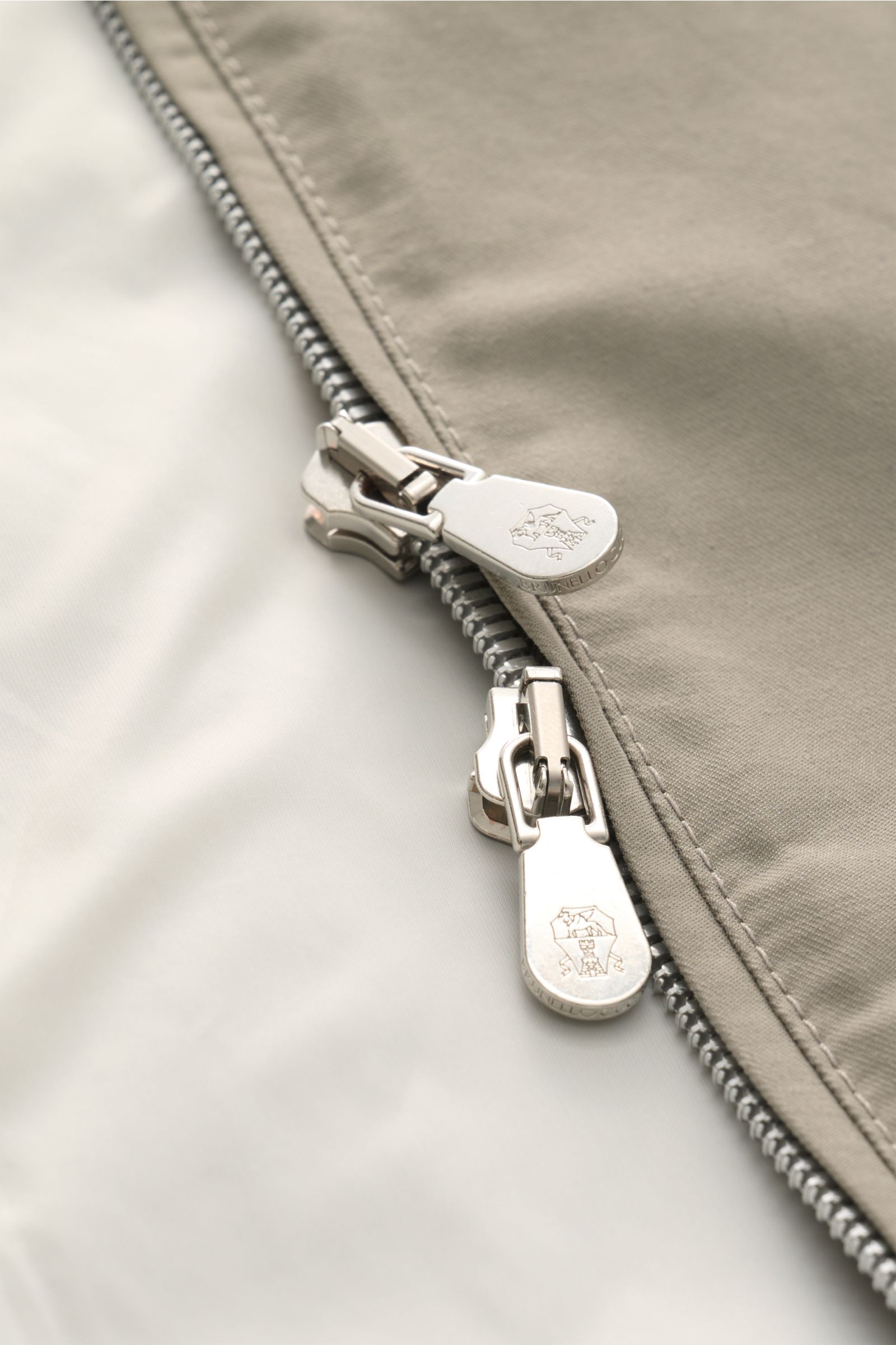 Close-up shot from above of the silver zipper details on the Brunello Cucinelli Blouson salbei, showcasing twill cotton-microfiber fabric, soft feel, water-repellent, and fine corduroy accents.