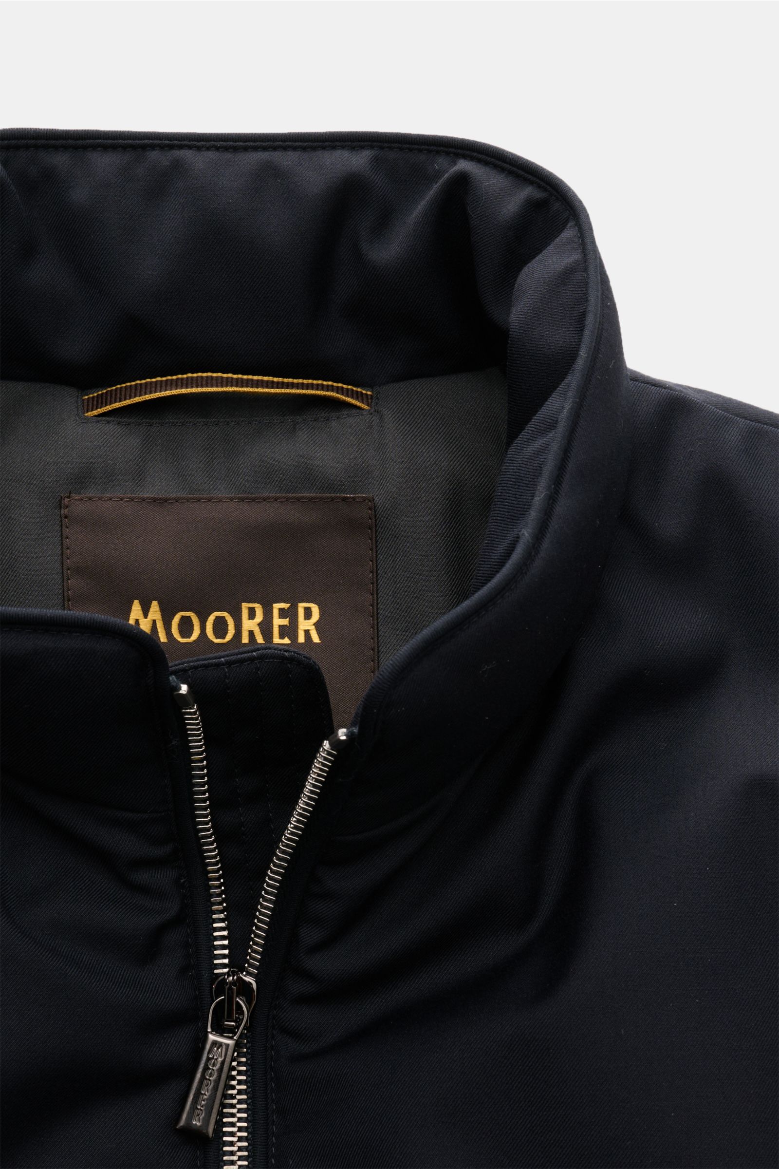 Nahaufnahme der Moorer Daunenweste 'Uros' dark navy, stehend mit Reißverschluss, Stehkragen und edlem Garbadine-Gewebe.