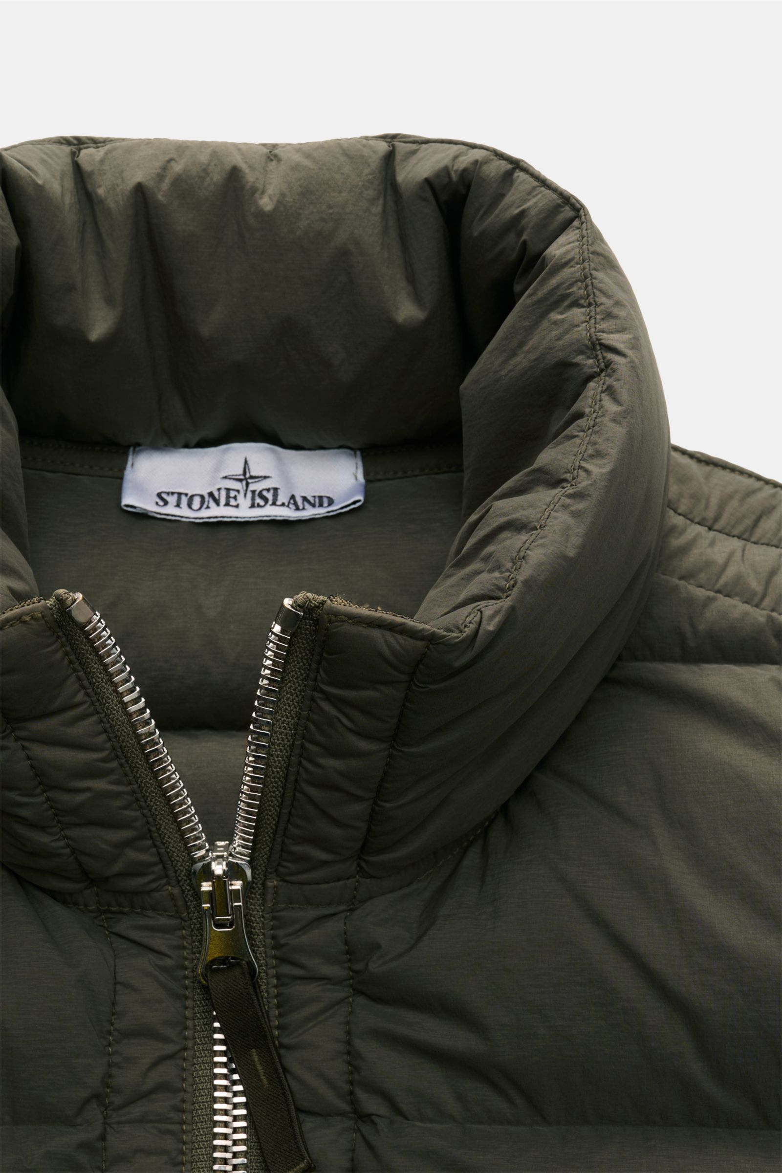 Close-up front view of Stone Island Down gilet 'Seamless Tunnel Nylon Down-TC' olive showing high collar and zipper details.

The outdoor gilet 'Seamless Tunnel Nylon Down-TC' by STONE ISLAND has a warm, responsibly produced down lining and an innovati