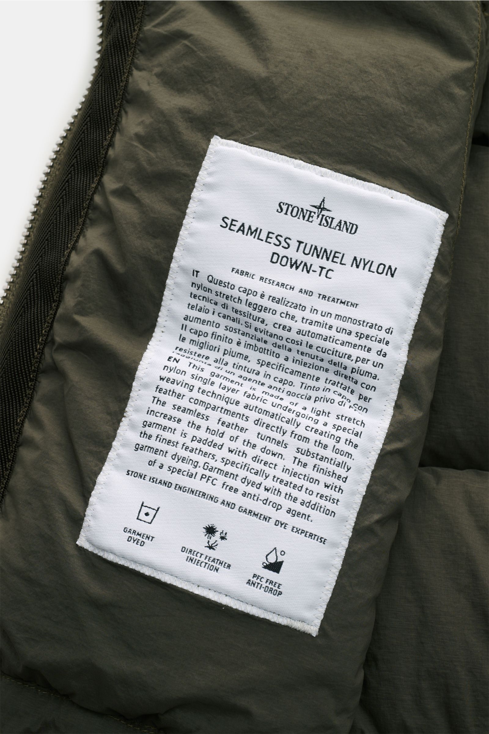 Close-up front-side view of Stone Island Down gilet 'Seamless Tunnel Nylon Down-TC' olive showing fabric texture and sewn-in label with care details.

The outdoor gilet 'Seamless Tunnel Nylon Down-TC' by STONE ISLAND has a warm, responsibly produced do