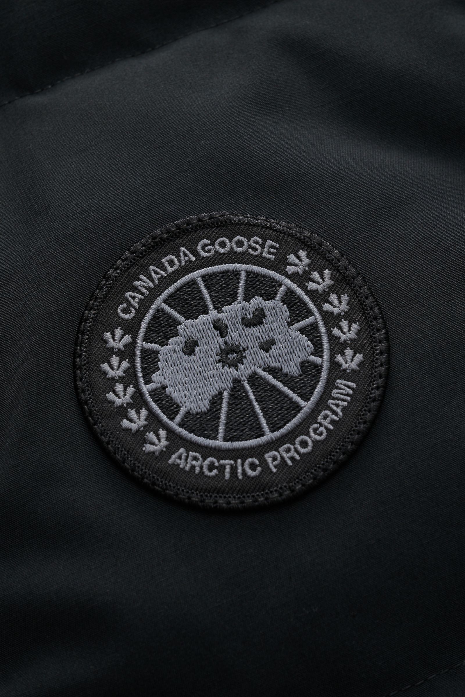 Canada Goose Daunenweste 'Garson' schwarz Nahaufnahme des CANADA GOOSE-Weblabels auf wasserabweisendem Material, Mix aus Baumwolle und Microfaser.