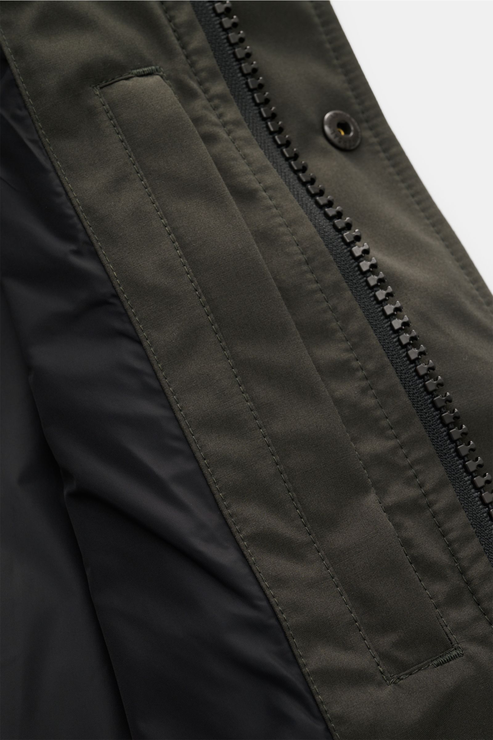 Nahaufnahme von der wasserabweisenden Canada Goose Daunenweste 'Garson' graugrün mit robustem Zwei-Wege-Reißverschluss und schräger Leistentasche.