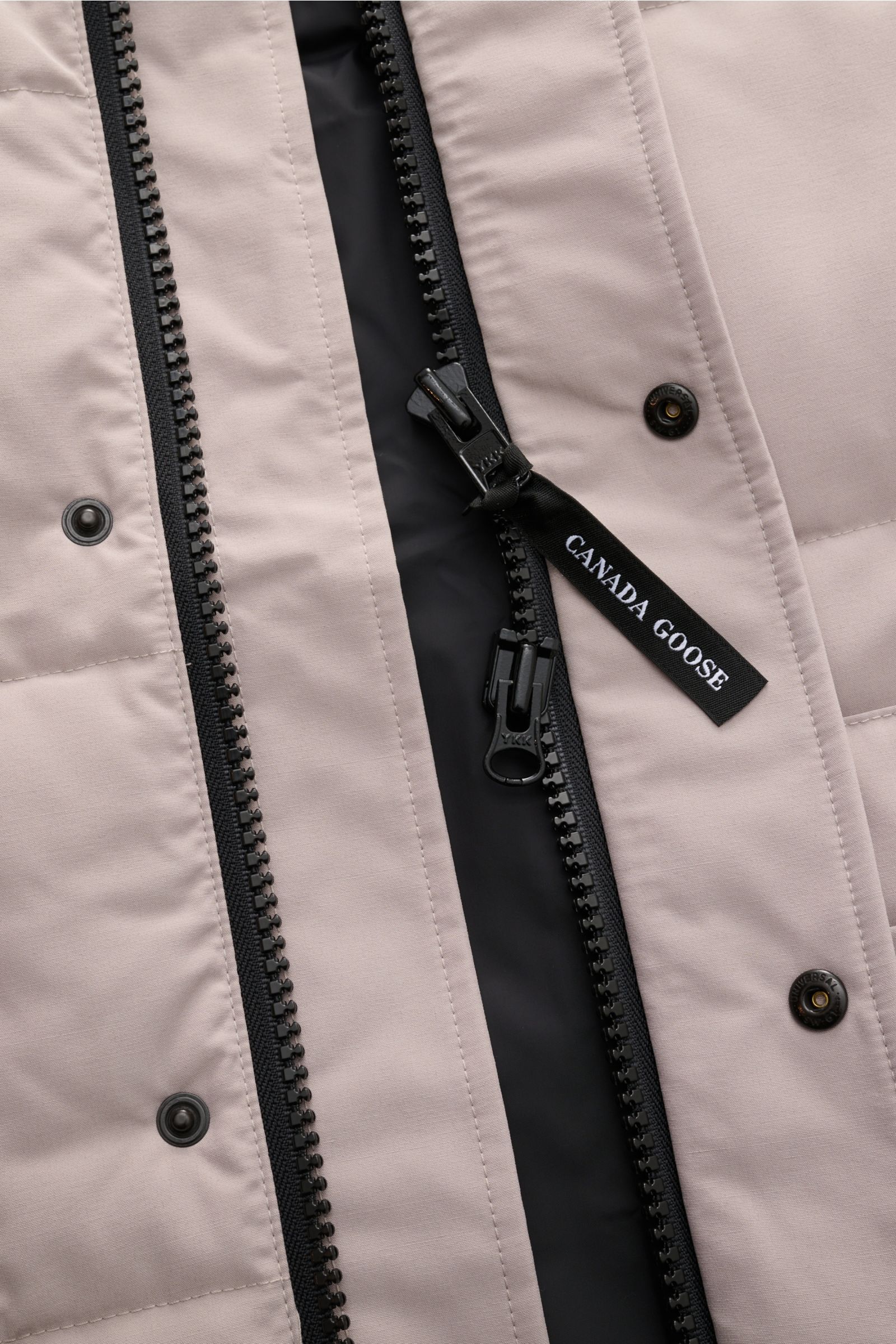 Canada Goose Daunenweste 'Freestyle Crew' hellgrau, Nahaufnahme des robusten Zwei-Wege-Reißverschlusses und wind- und wasserabweisendem Obermaterial.