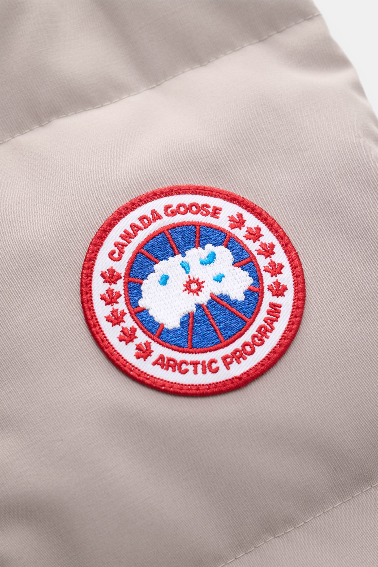 Canada Goose Daunenweste 'Freestyle Crew' hellgrau Nahaufnahme des roten Logos auf wind- und wasserabweisendem Microfaserstoff.