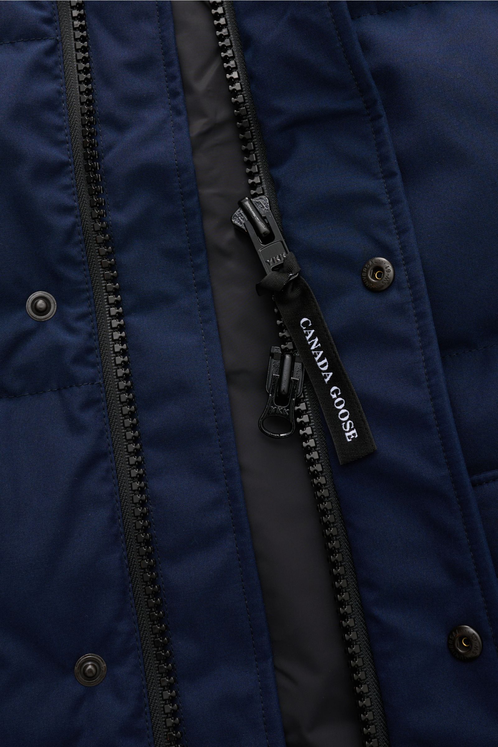 Nahaufnahme der Canada Goose Daunenweste 'Freestyle Crew' navy von vorne, mit sichtbarem robustem Zwei-Wege-Reißverschluss, Windblende mit Druckknöpfen und hochwertiger Microfaser.