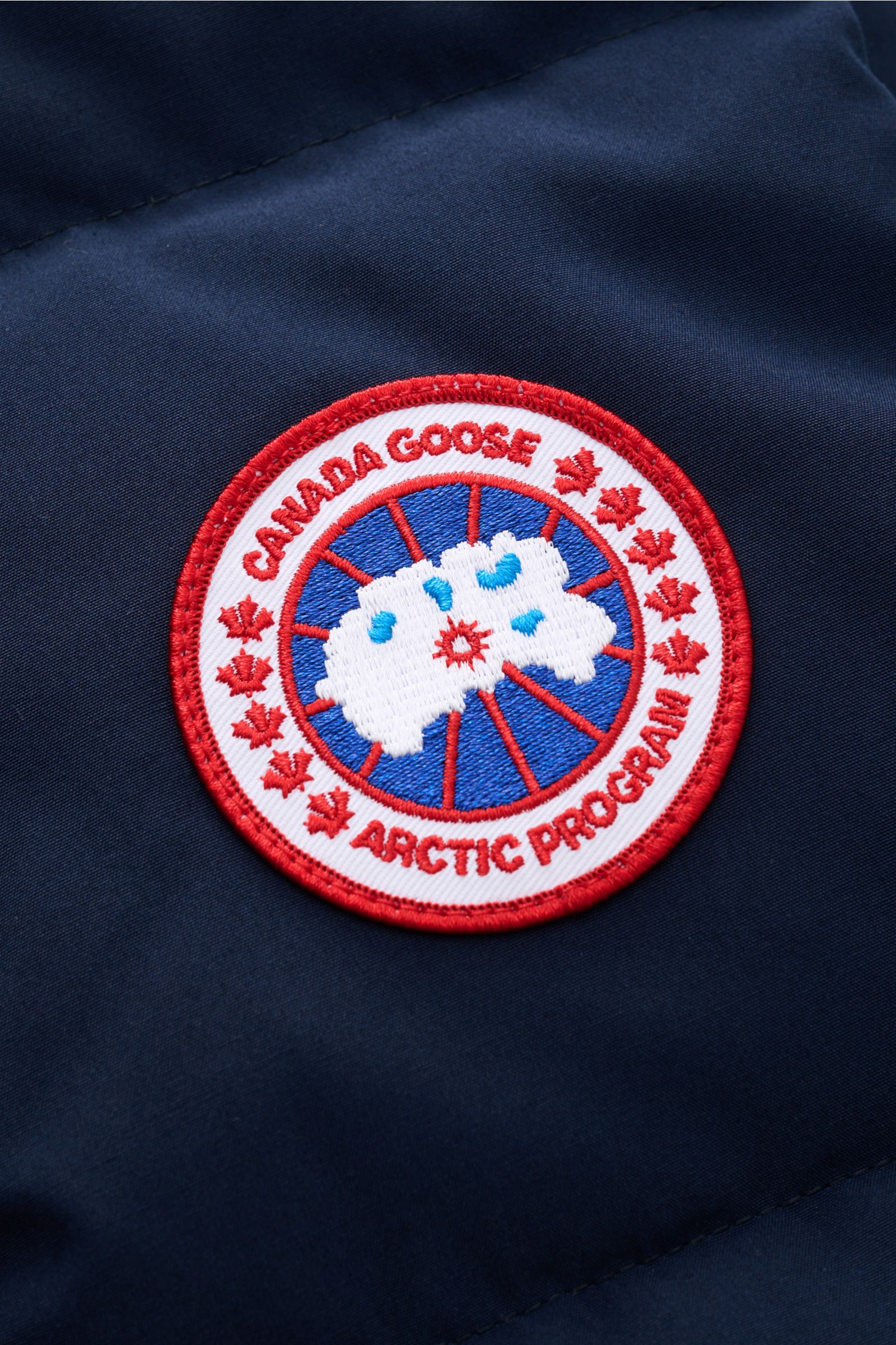 Canada Goose Daunenweste 'Freestyle Crew' navy im Detail: Nahaufnahme des roten CANADA GOOSE-Weblabels auf wind- und wasserabweisendem, navy Microfaserstoff.