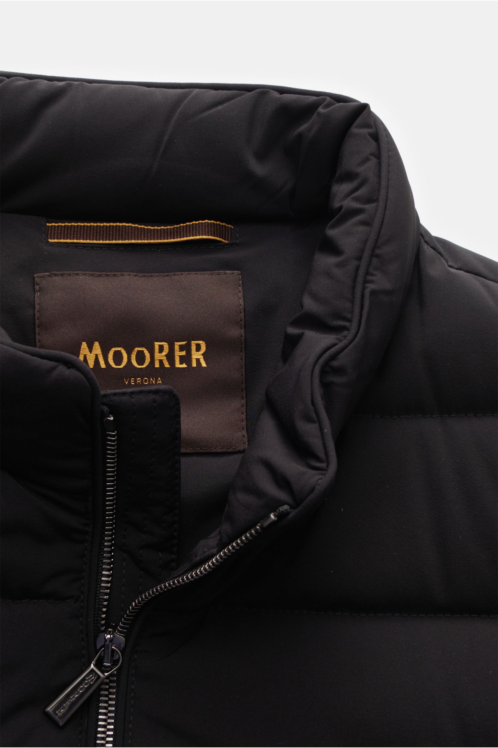 Nahaufnahme der Moorer Daunenweste 'Oliver' schwarz von vorne oben mit schmalem Stehkragen, Zwei-Wege-Reißverschluss und wasserabweisender Microfaser, gefüllt mit Gänsedaunen, Slim Fit, verdeckten Zipper-Taschen und zwei Innentaschen.