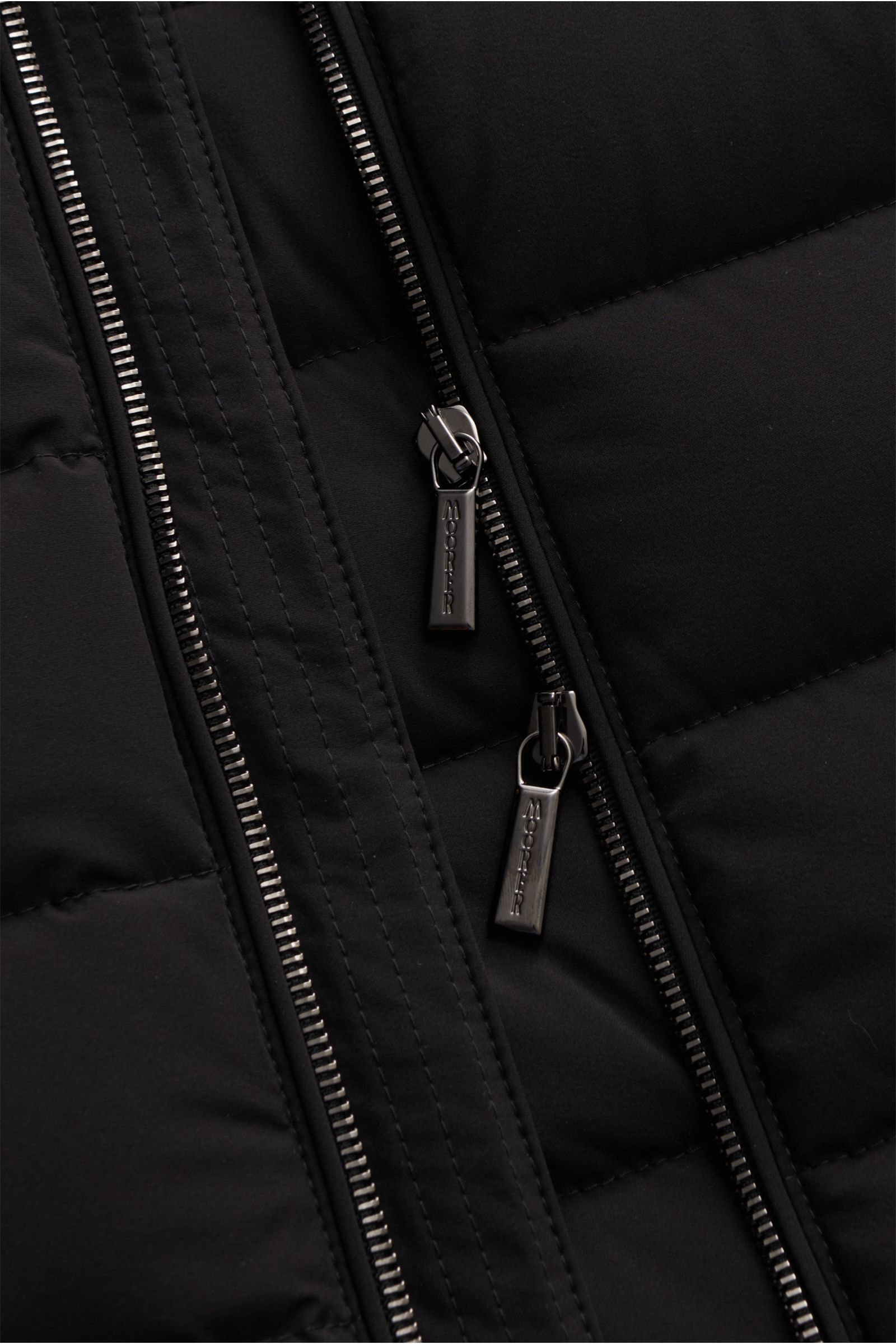 Nahaufnahme der Moorer Daunenweste 'Oliver' schwarz mit wasserabweisender Microfaser, zwei-Wege-Reißverschluss und verdeckten Zipper-Taschen.