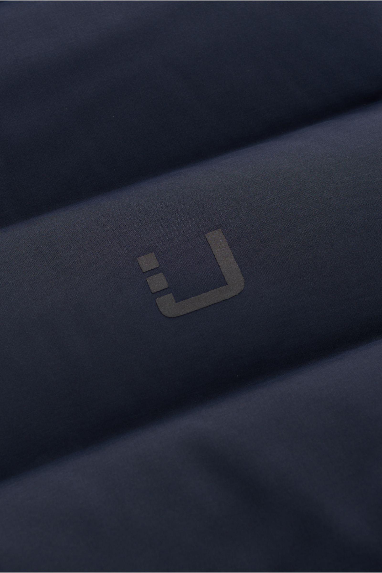 Nahaufnahme der UBR Daunenweste 'Sonic' navy aus hochwertiger, elastischer Microfaser mit weichem Griff, wasserabweisend, ultraleichter Daunenfüllung, Slim Fit, Zwei-Wege-Reißverschluss, hochschließendem Kragen, Zipper-Taschen, reflektierendem Logo, elast