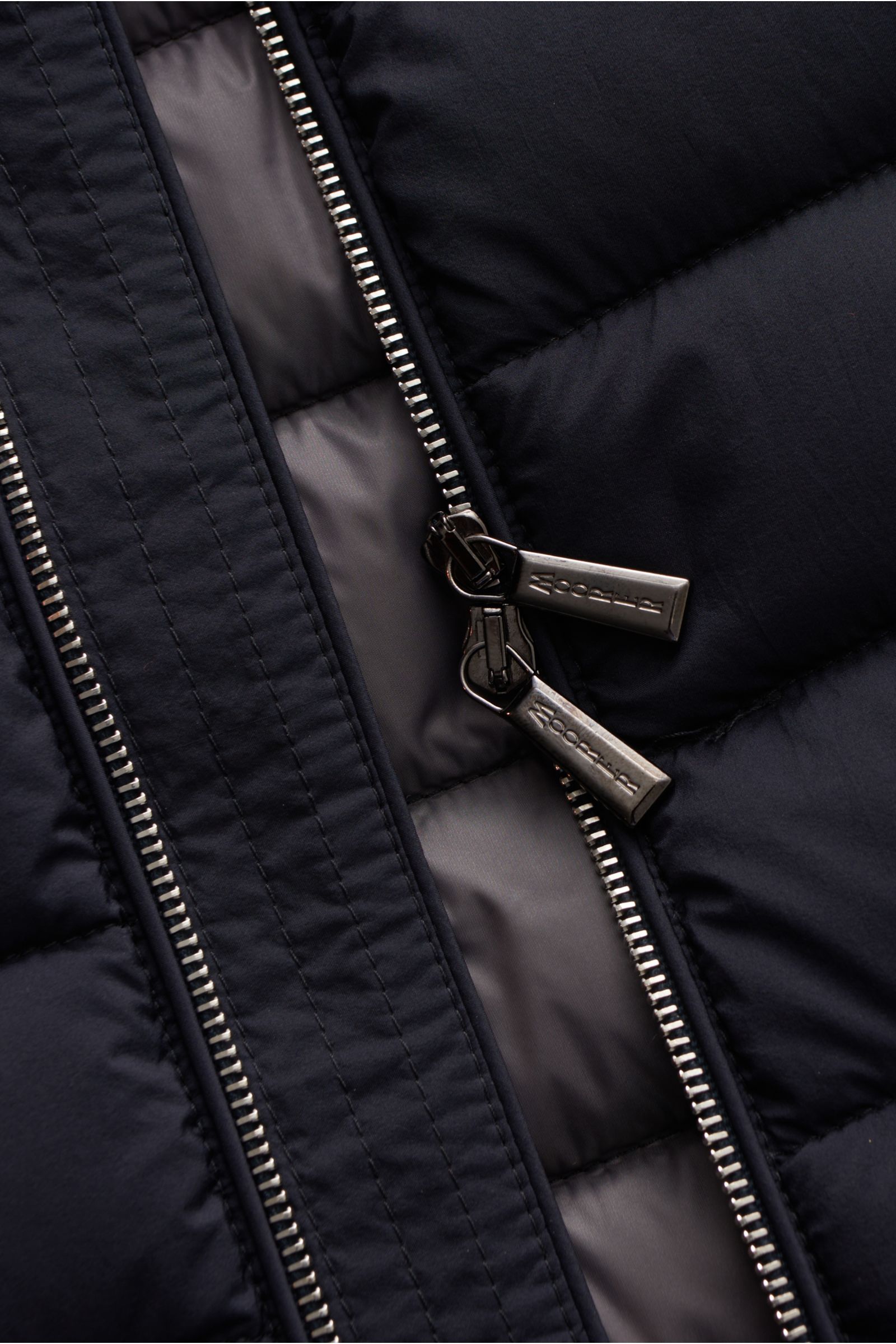 Nahaufnahme der geöffnete Moorer Daunenweste 'Calaf' navy mit zwei-Wege-Reißverschluss, atmungsaktiver Microfaser und Gänsedaunenfüllung.