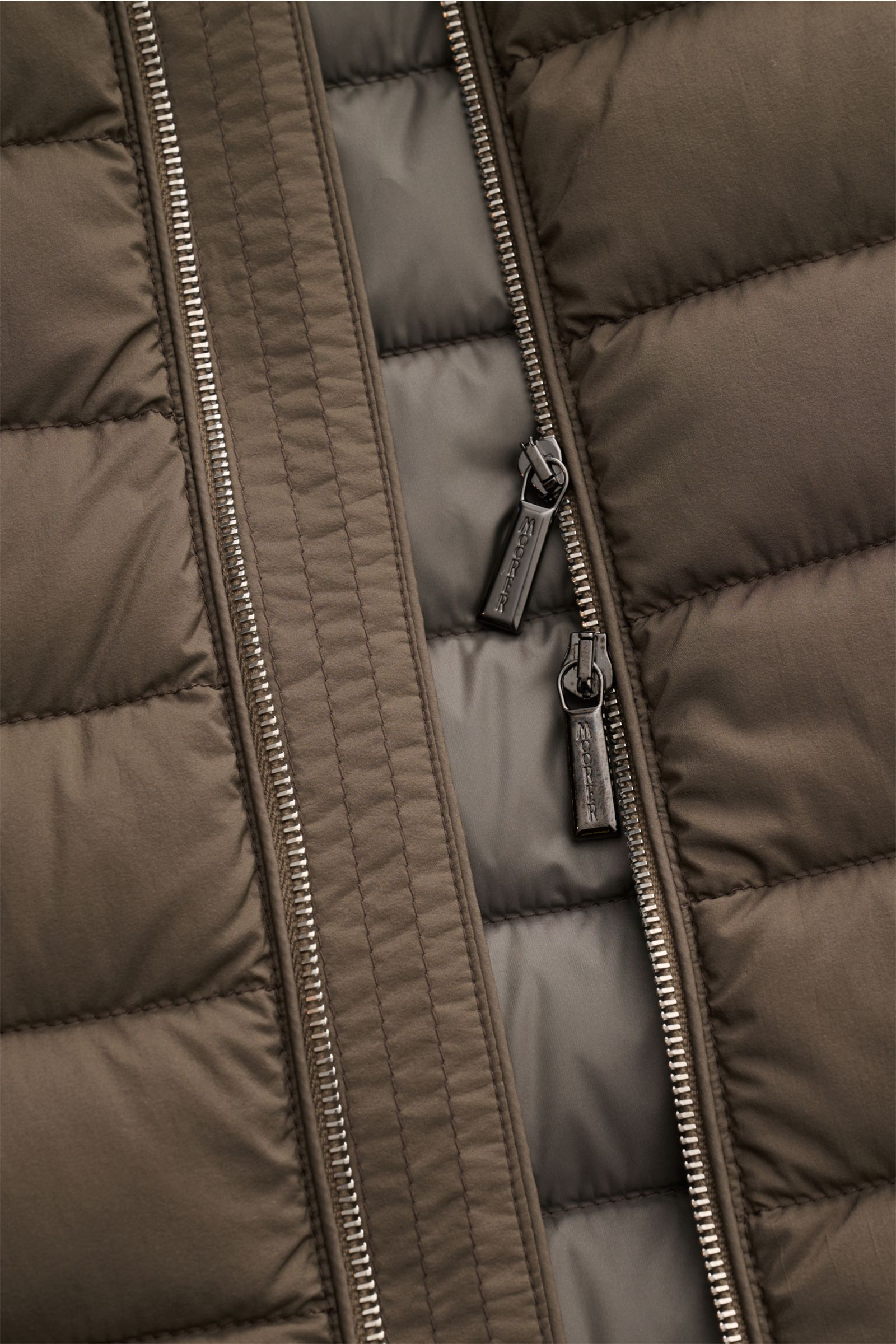 Close-up front view of the Moorer Daunenweste 'Calaf' dark olive, showing the double zipper with branded pulls on the quilted, matte, water-repellent microfiber fabric filled with soft Siberian goose down for lightweight warmth. 

Luxus in allerhöchste