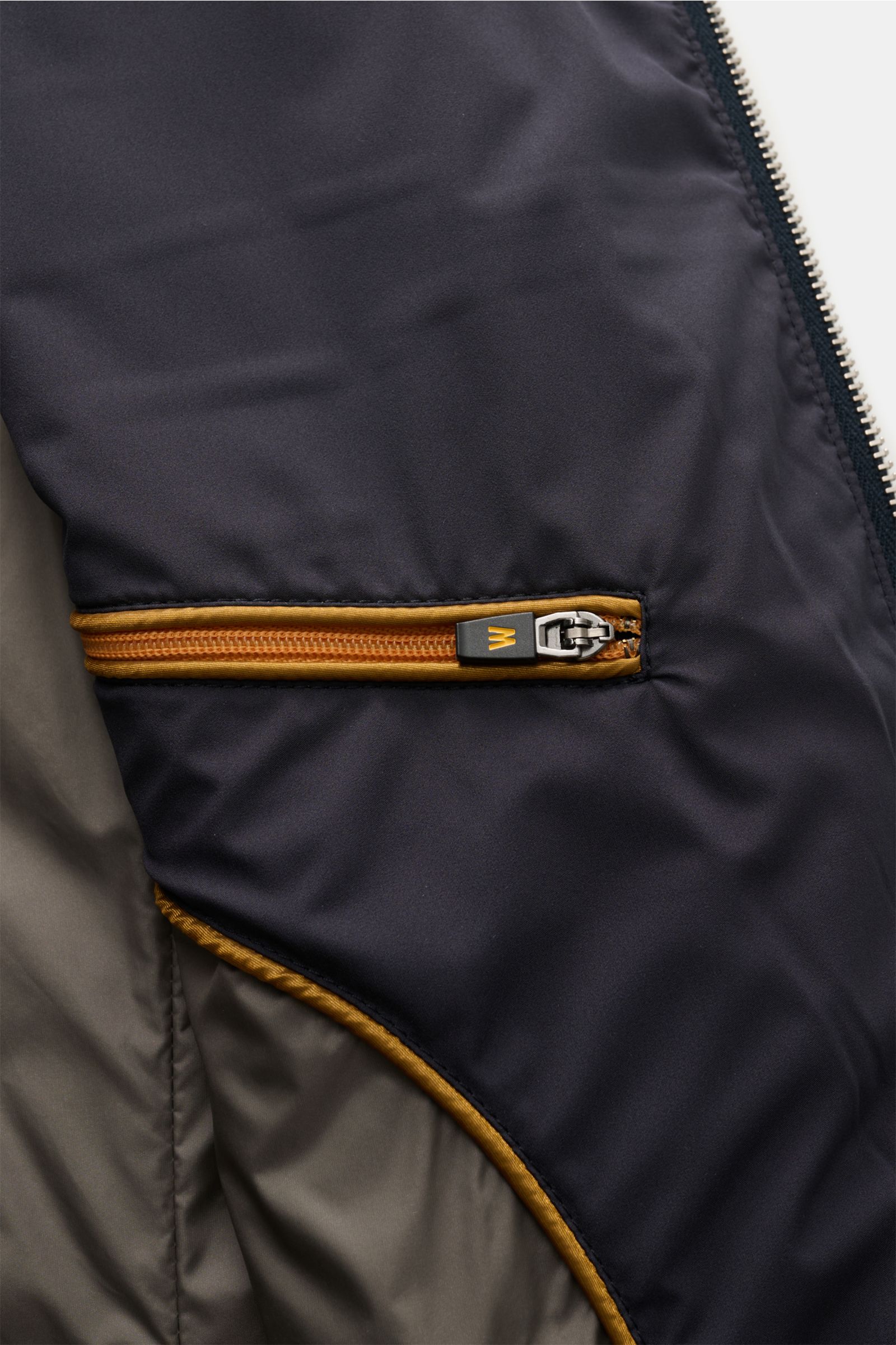 Nahaufnahme der Innenseite der Moorer Outdoor-Weste 'Senio-Skt' dark navy mit wasserabweisender Microfaser, leichter Füllung, Innentasche und gelben Zipperdetails.