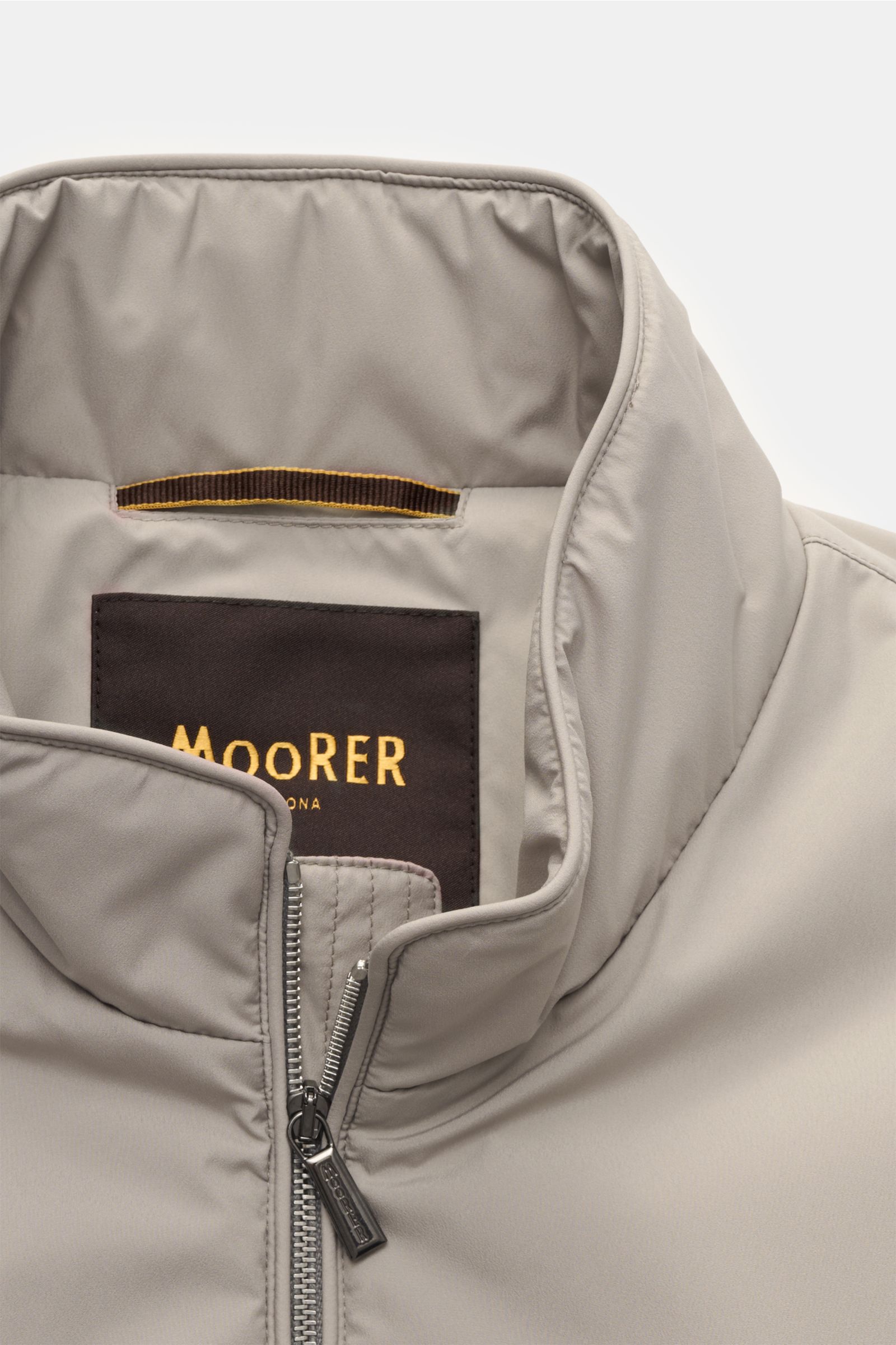 Close-up front view of the beige Moorer Outdoor-Weste 'Senio-Skt' showcasing its slim fit, water-repellent microfiber, smooth texture, narrow stand-up collar, two-way zipper, angled zippered front pockets, and inner pocket.