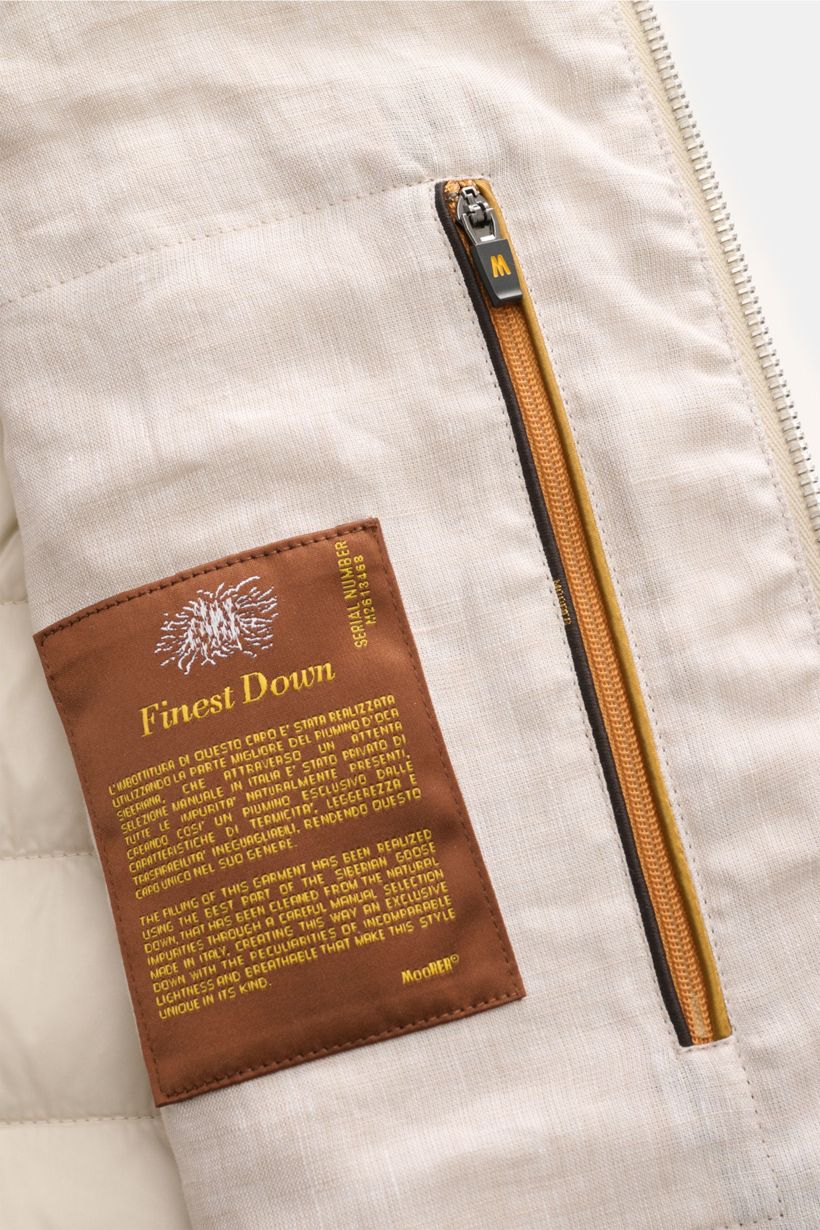 Close-up interior view of the Moorer Down gilet 'Calaf' beige mottled, showing the finely stitched brown 'Finest Down' label and a mustard-yellow concealed zip pocket on soft pure linen fabric, highlighting luxury Siberian goose down lining and narrow cro