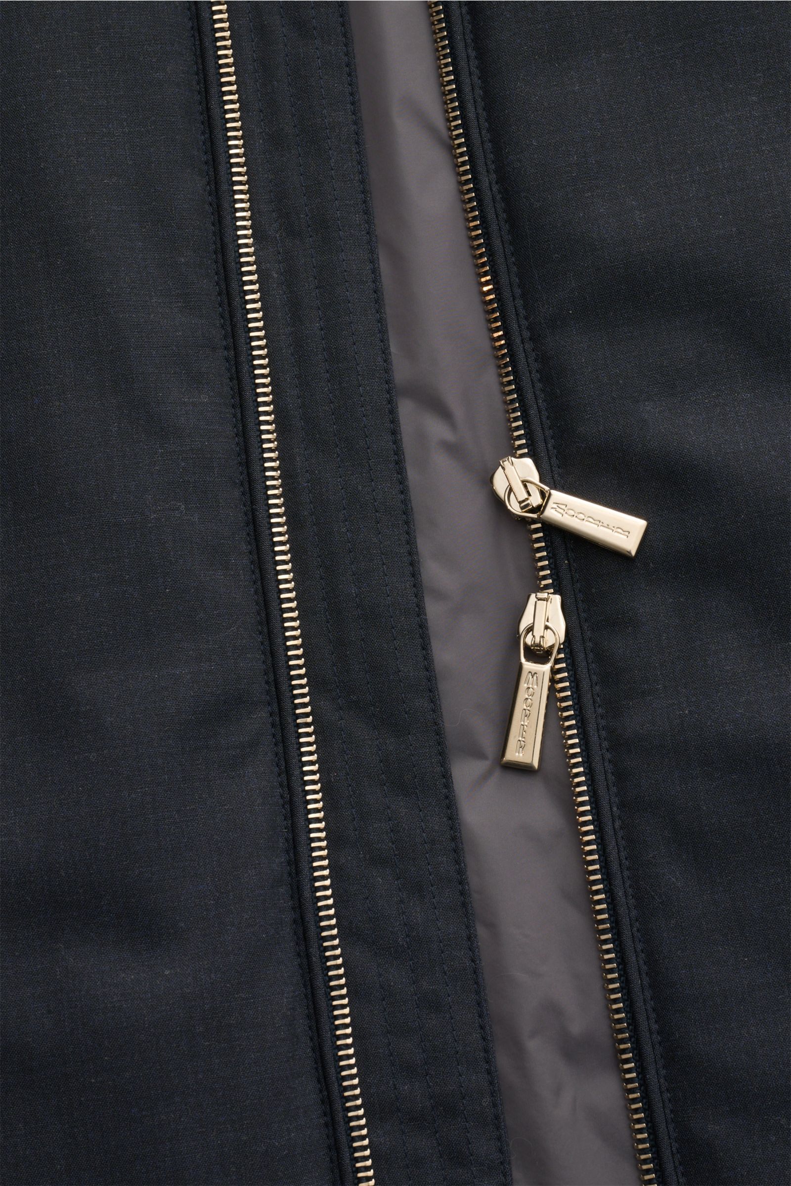Nahaufnahme der zweiwege-Reißverschlüsse der Moorer Outdoor-Weste 'Senio-Bt' dark navy mit glattem Griff aus elastischer Schurwolle.