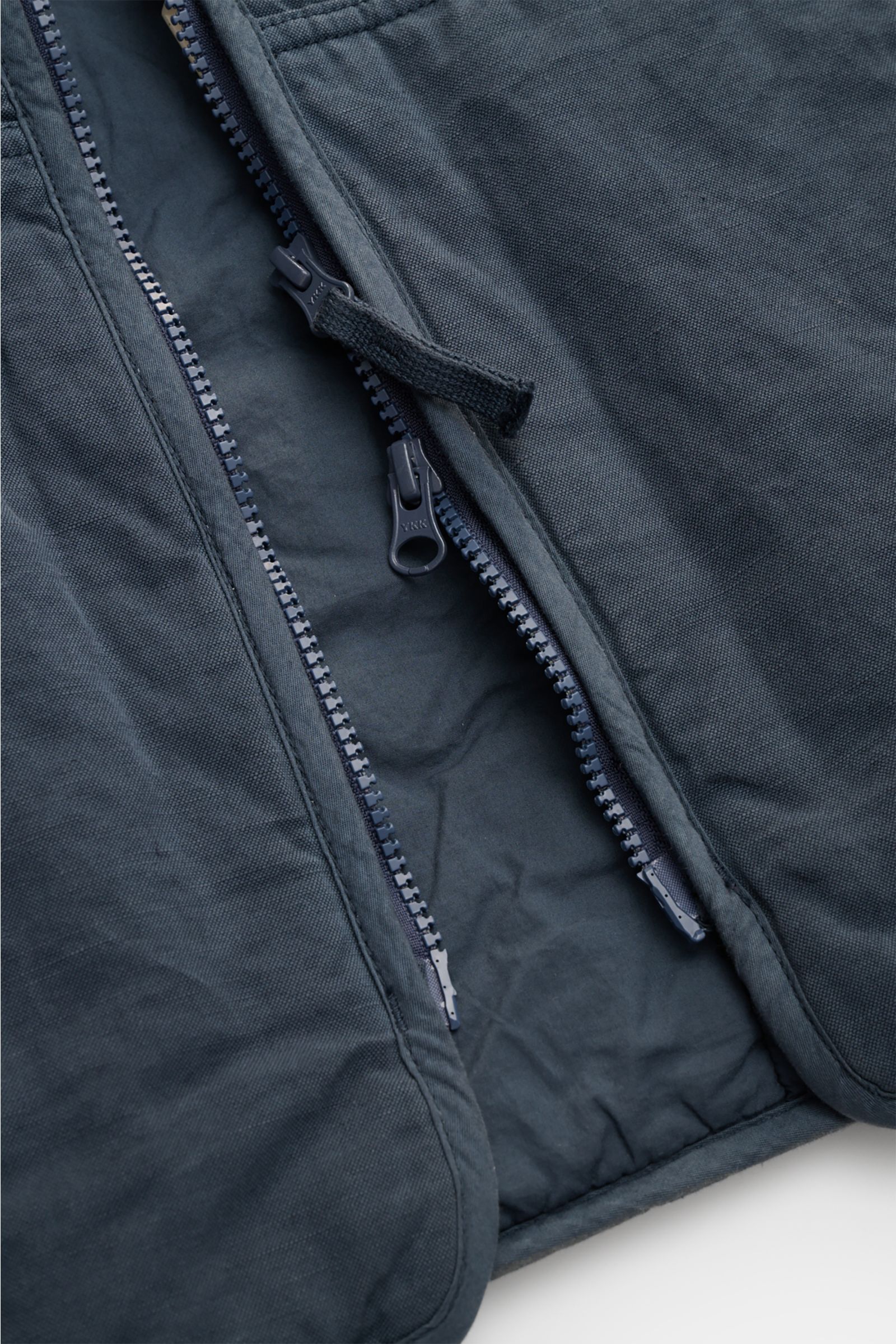 Nahaufnahme der Stone Island Outdoorweste 'Ghost Piece' graublau mit Baumwolle-Leinen-Mix, Slim Fit, Blousonkragen und Zwei-Wege-Reißverschluss.