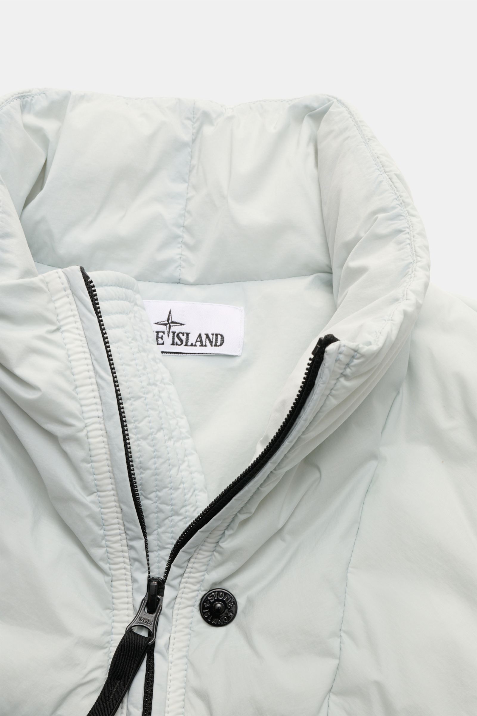 Stone Island Daunenweste 'Seamless Tunnel Nylon Down' hellgrau, Nahaufnahme von Kragen und Zwei-Wege-Reißverschluss, wind- und wasserabweisend, elastisches Gewebe.