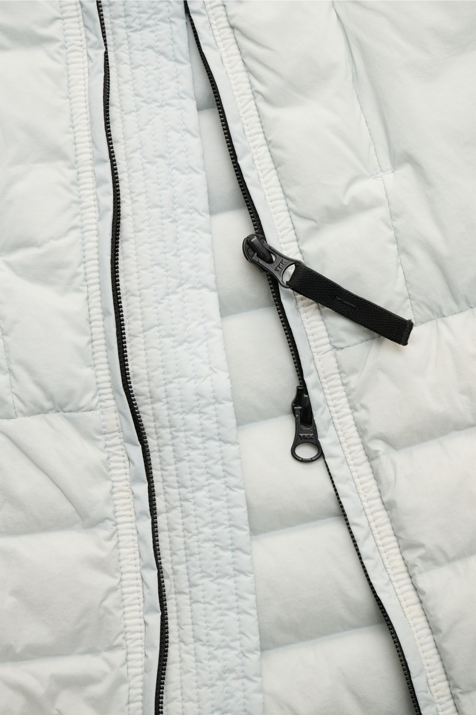 Nahaufnahme der hellgrauen Stone Island Daunenweste 'Seamless Tunnel Nylon Down' mit zwei-Wege-Reißverschluss, elastischem Gewebe und wattiertem Kragen.