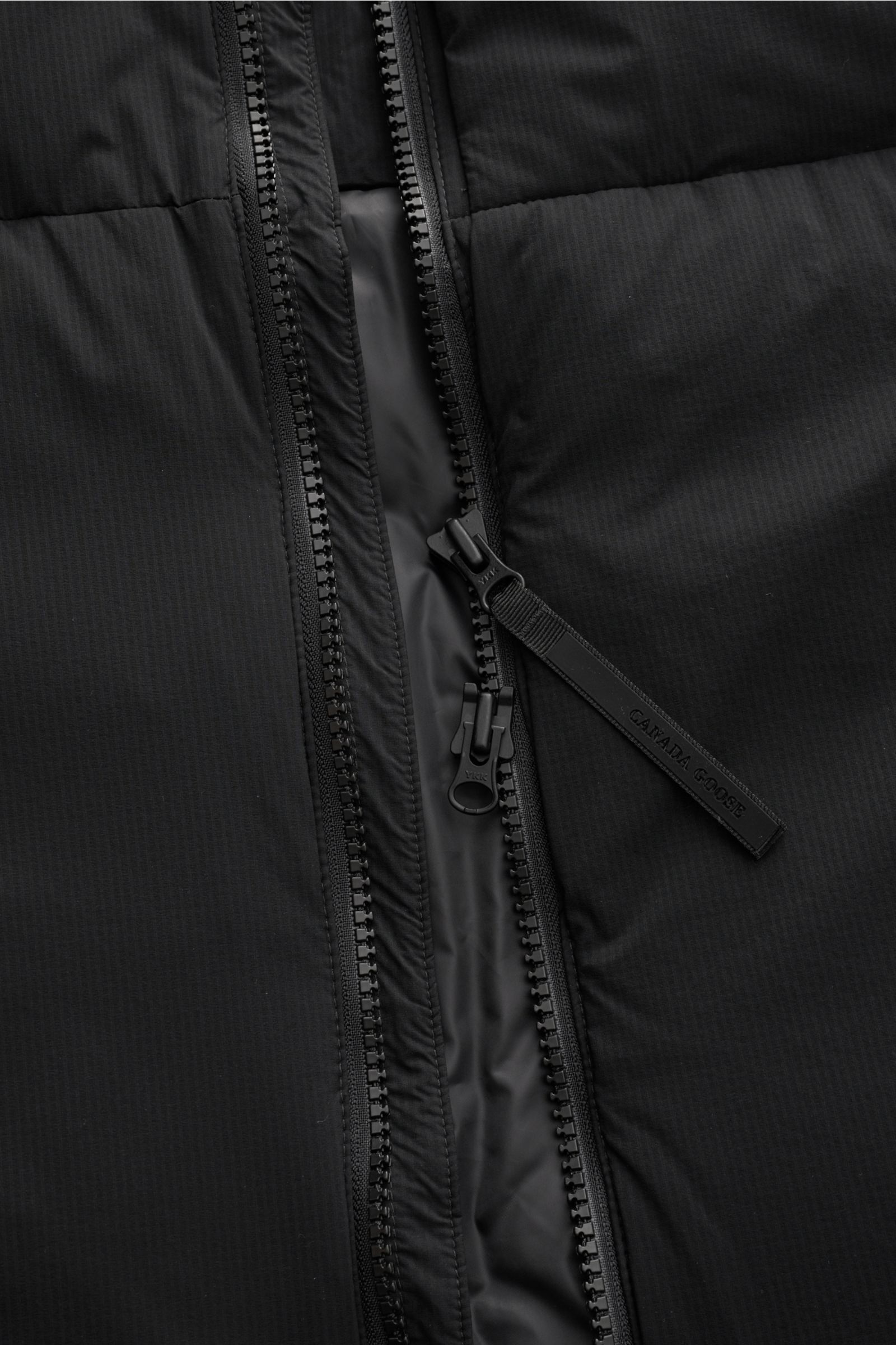 Canada Goose Daunenweste 'Lodge' schwarz, Detailaufnahme des robusten Zwei-Wege-Reißverschlusses mit Ripstop-Obermaterial.