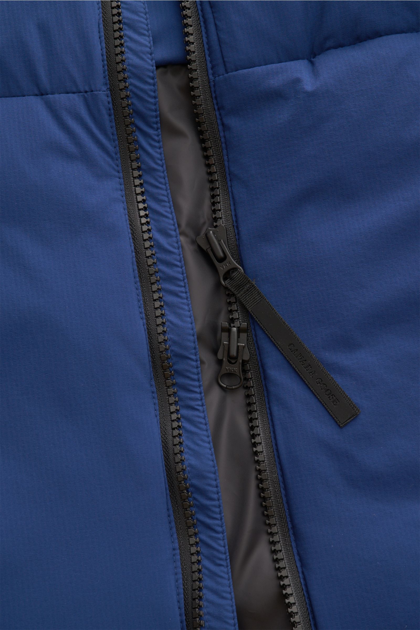 Close-up front view of the Canada Goose Down gilet 'Lodge' blue showing a robust two-way black zipper with a branded pull tab on high-quality ripstop fabric.

Description: The super lightweight 'Lodge' down gilet by CANADA GOOSE with high-quality ripst