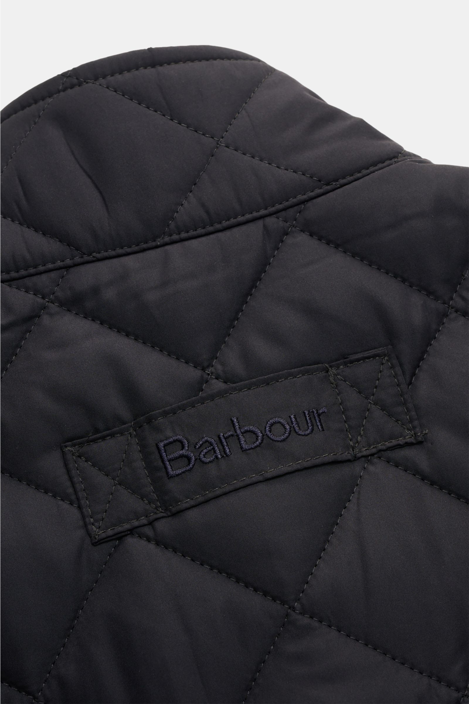 Barbour Steppweste 'New Lowerdale' dark navy in Nahaufnahme von oben, gesteppte Microfaser mit tonalem Logo-Stitching.