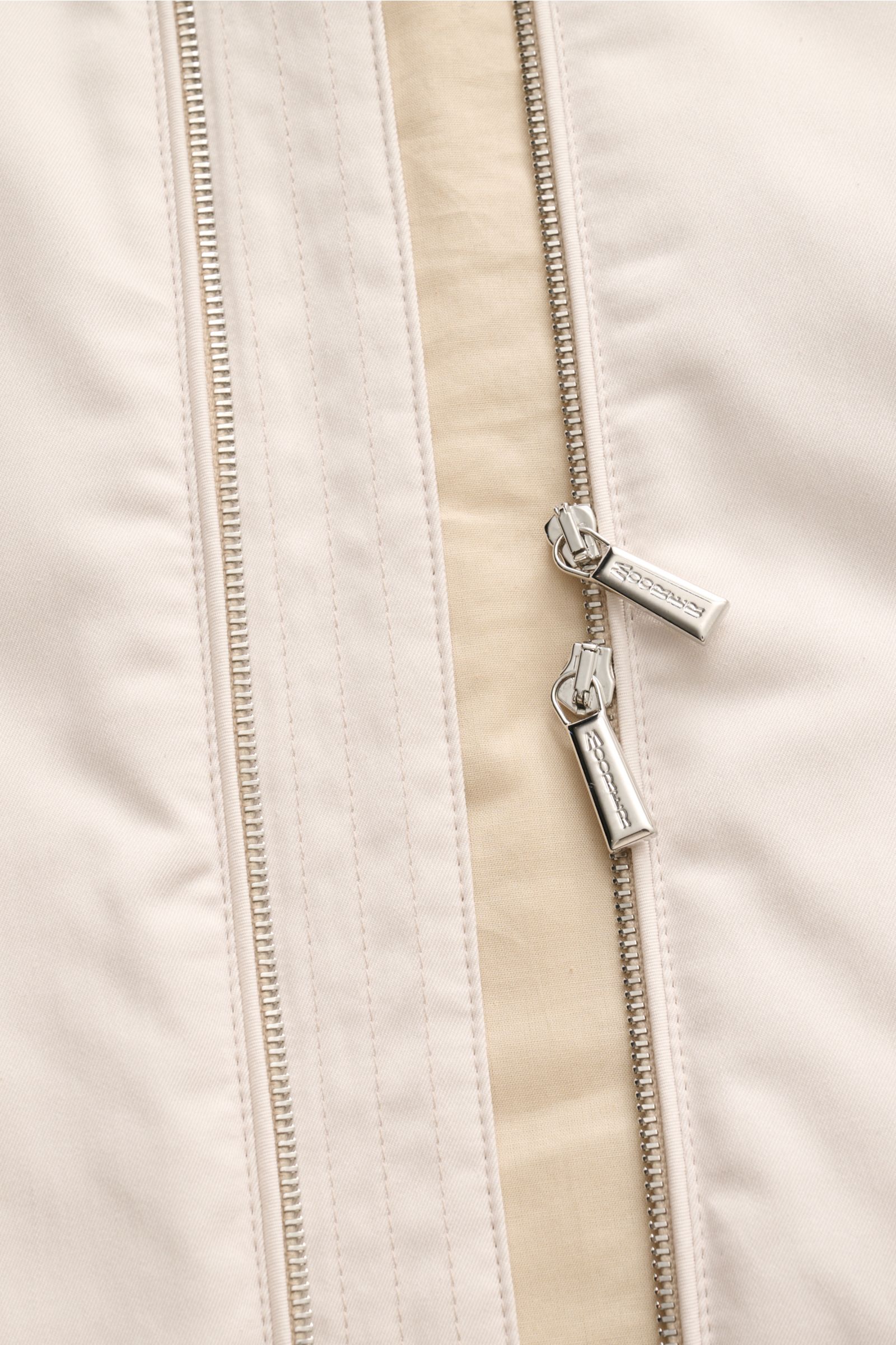 Nahaufnahme der cremefarbenen Moorer Outdoor-Weste 'Senio-Si' mit zwei-Wege-Reißverschluss, glattem Griff und feiner Sea Island Baumwolle.