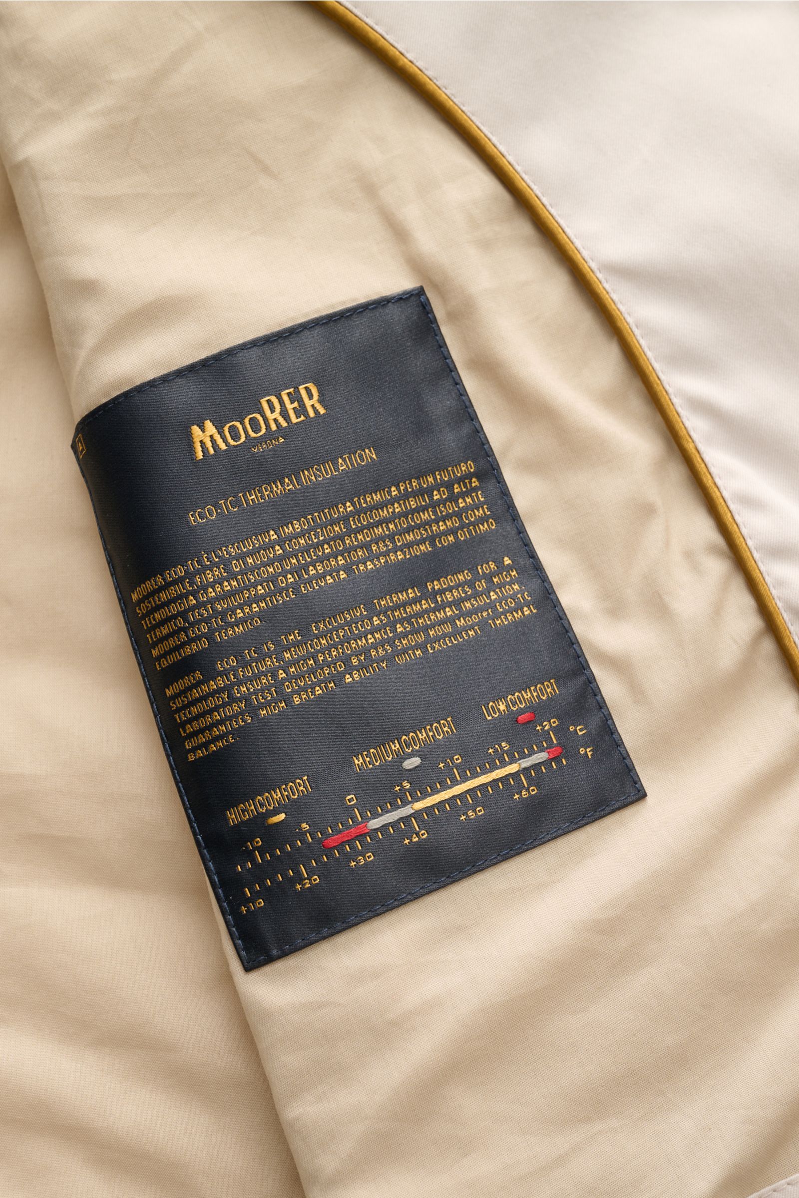 Nahaufnahme der Innenseite der Moorer Outdoor-Weste 'Senio-Si' creme mit schwarzem Label, Sea Island Baumwolle und Seidenmix, glattem Griff, leichter Füllung, slim Fit, schmalem Stehkragen, zwei-Wege-Reißverschluss, schrägen Zipper-Fronttaschen und Innent