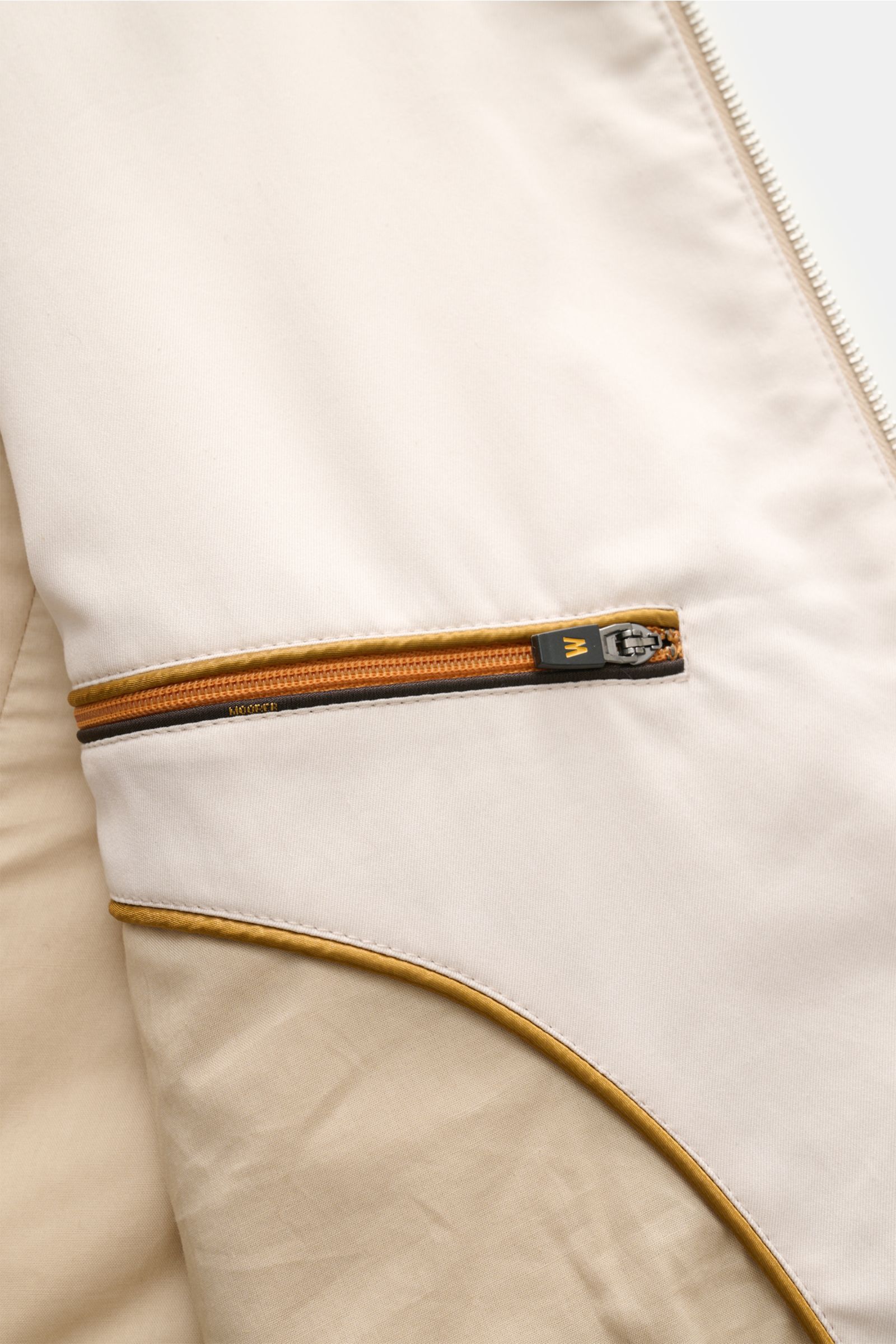 Nahaufnahme der Innentasche der Moorer Outdoor-Weste 'Senio-Si' creme aus Sea Island Baumwolle und Seide, glatter Griff, schmaler Stehkragen, zwei-Wege-Reißverschluss, schräge Zipper-Fronttaschen, Slim Fit.