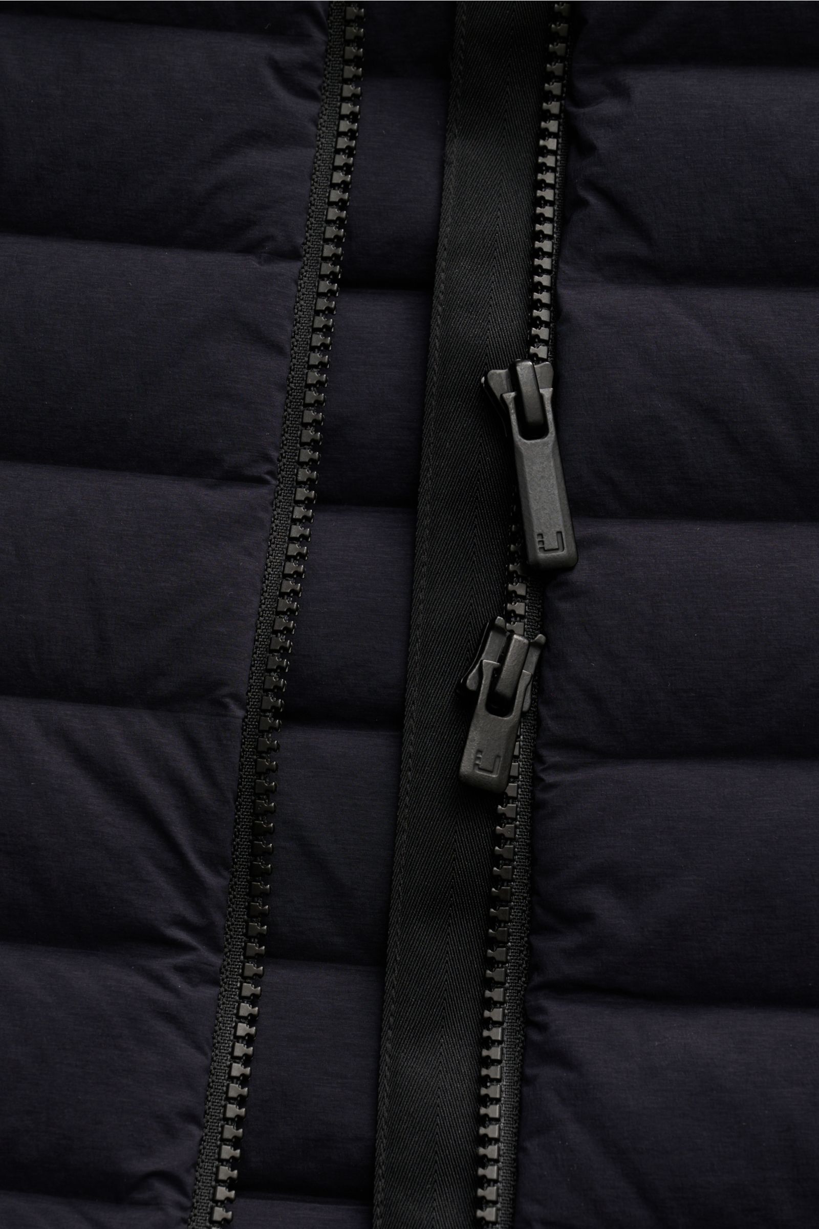 Close-up front view of the black two-way zipper on the UBR Daunenweste 'Supersonic' navy, made of elastic microfiber with ultralight down filling.