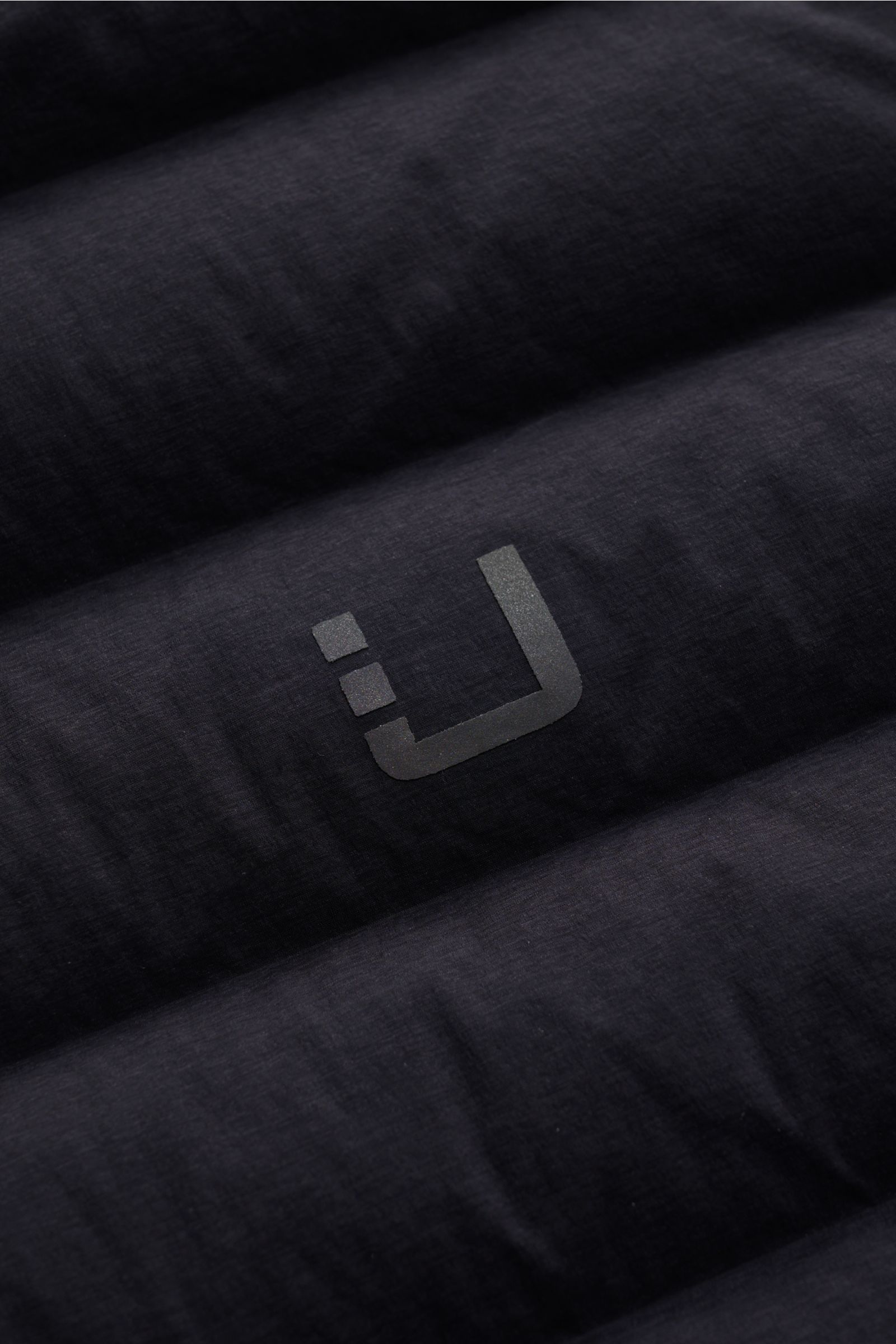 Close-up front view of UBR Daunenweste 'Supersonic' navy showing ultralight down filling, elastic microfiber fabric, and reflective logo print.