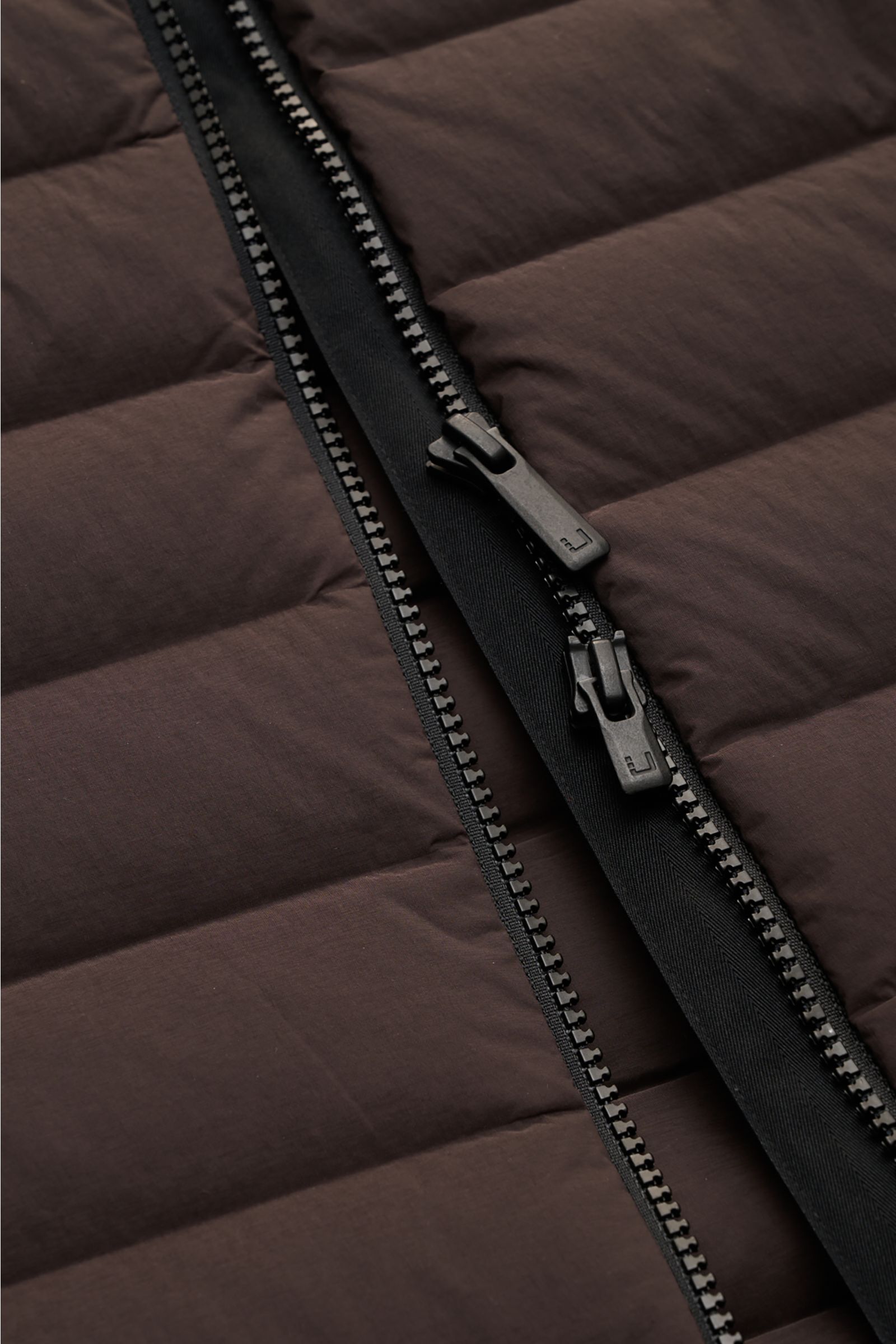 Close-up front view of the zipper on the UBR Down gilet 'Supersonic' grey-brown, showing high-quality stretchy microfibre fabric with ultra-light down lining, two-way zip, water repellent finish, and slim fit design with elastic hem and cuffs.