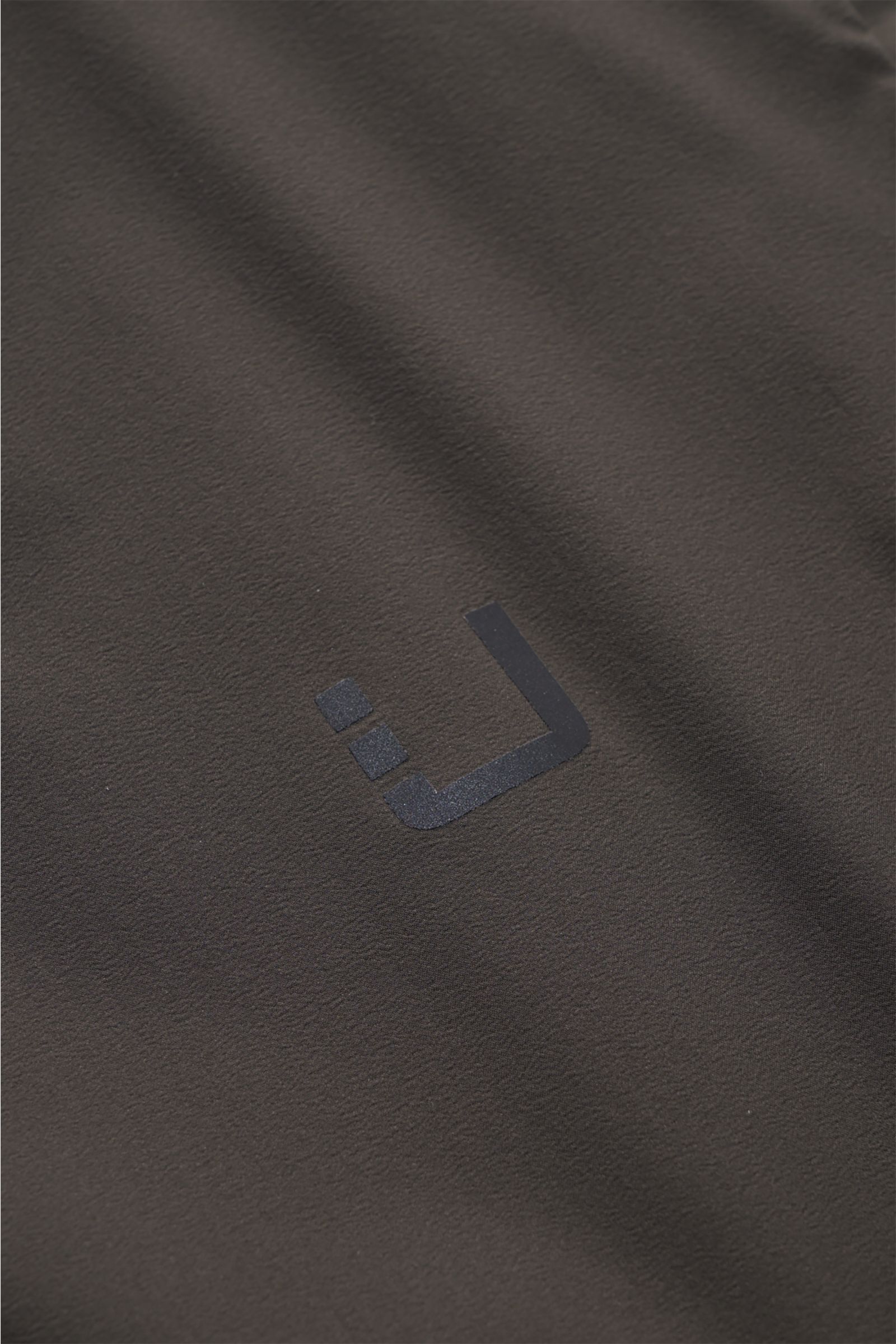 UBR Outdoor-Weste 'Raptor' oliv, Detailaufnahme des reflektierenden Logos auf hochwertiger Microfaser mit weichem Griff und leichter Wattierung.