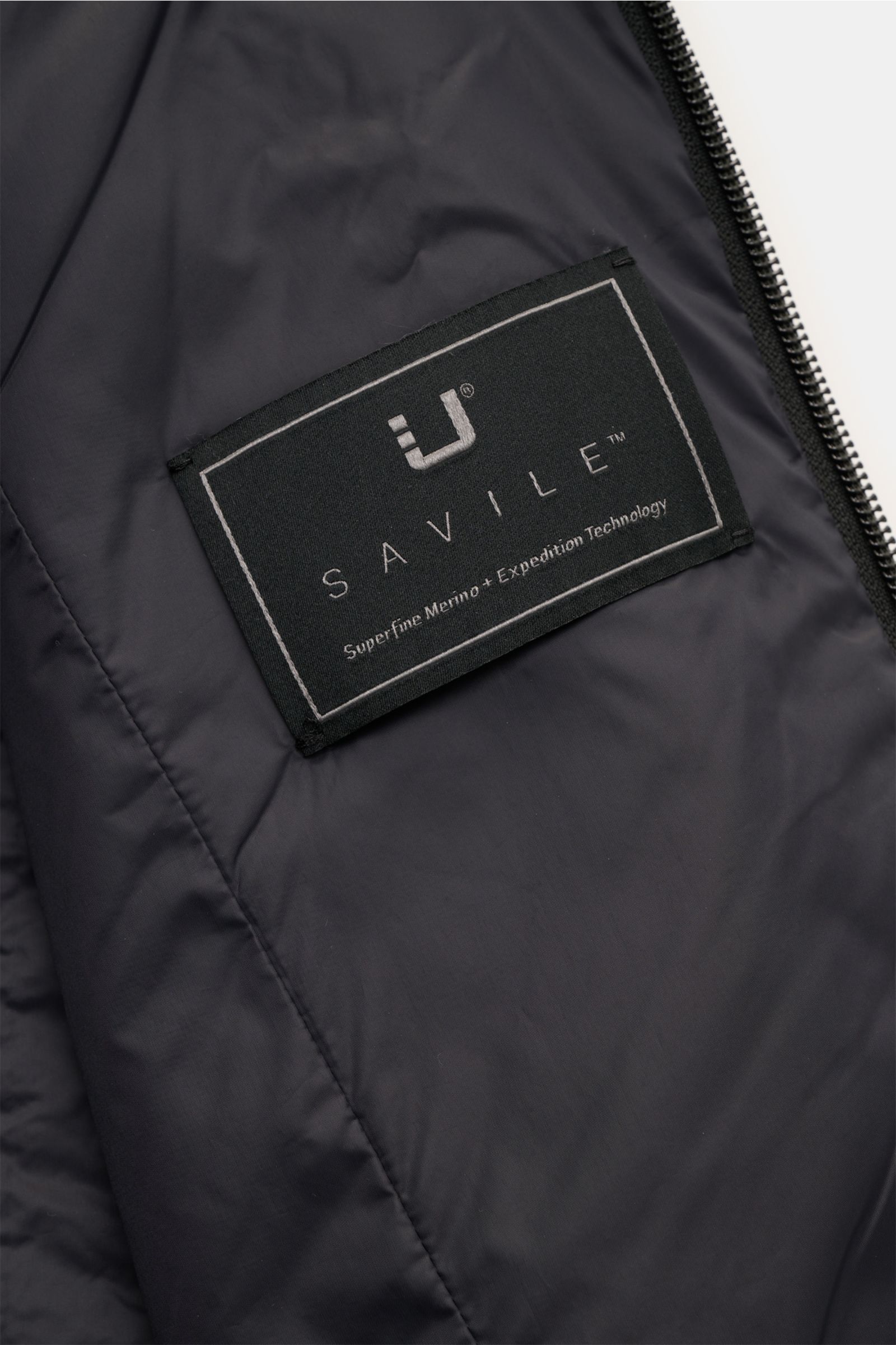 Close-up interior view of the UBR Outdoorweste 'Raptor Savile' navy meliert showing the Savile label on smooth lining with two-way zipper edge.