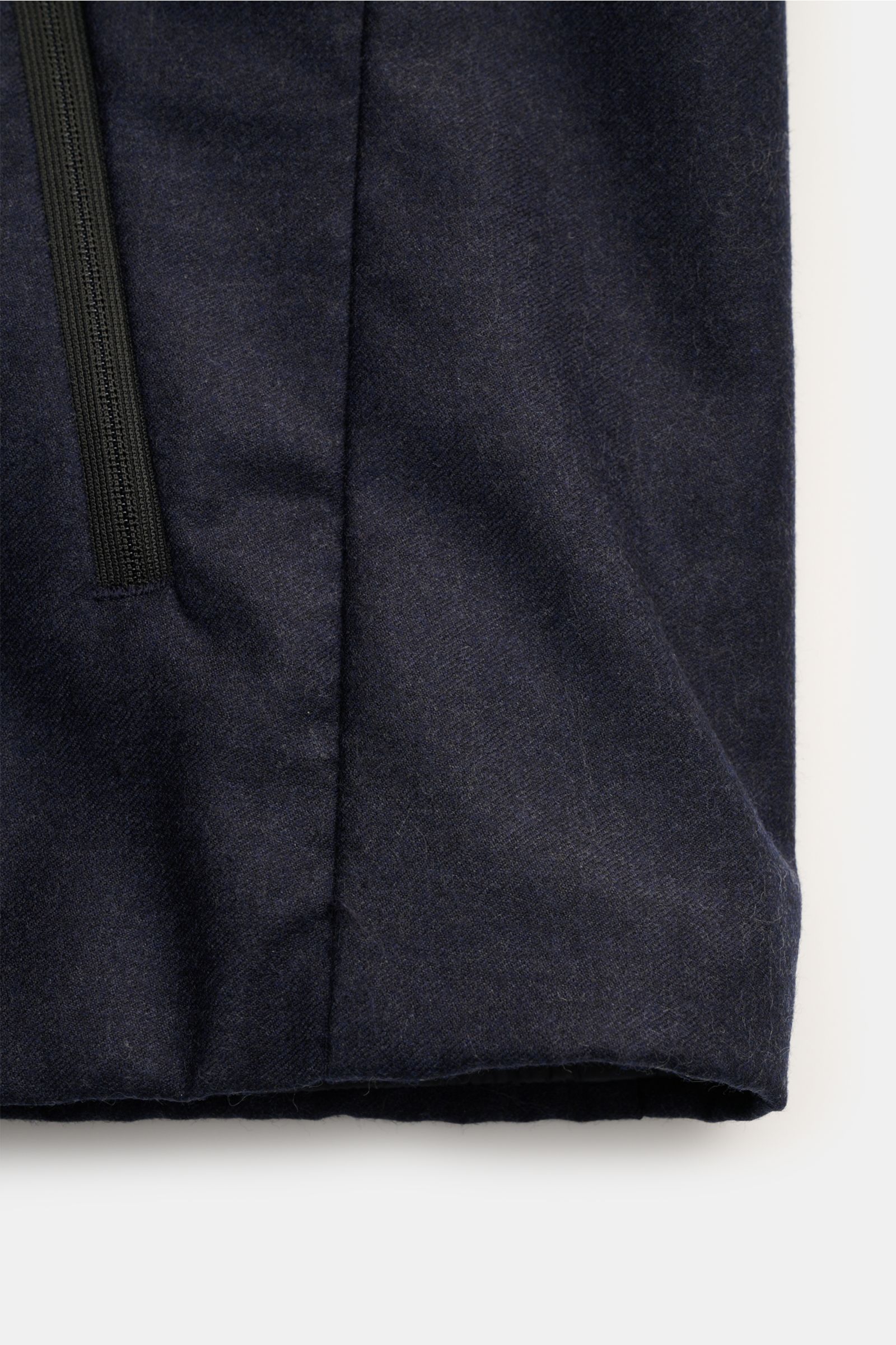Close-up front view of the lower part of the UBR Outdoorweste 'Raptor Savile' navy meliert, showing soft pure wool fabric, slim fit, two-way zipper, angled welt pocket, and smooth lining, designed for comfort and timeless urban outdoor style in the transi