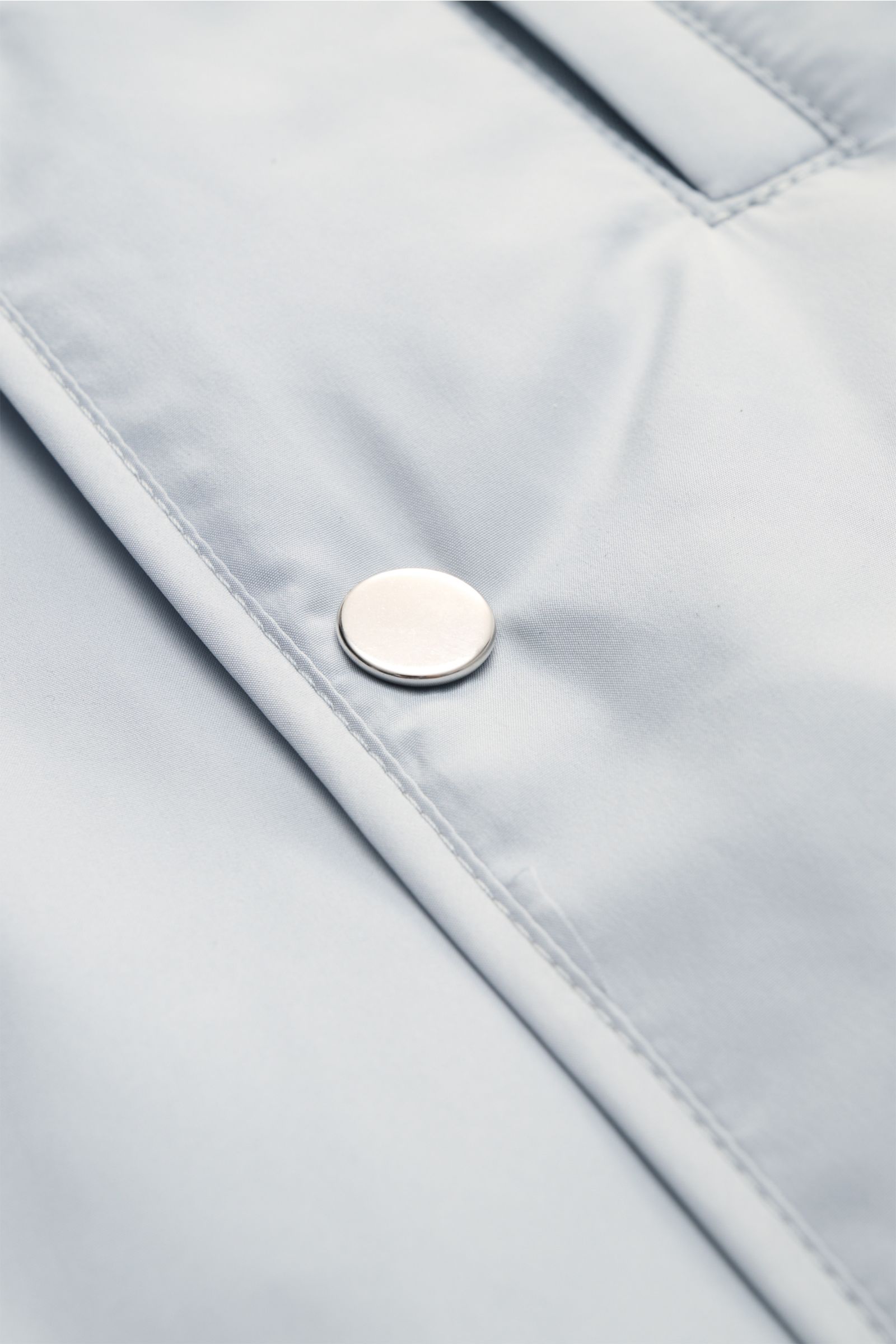 Nahaufnahme der silbernen Fünf-Knopf-Leiste der pastellblauen 04651/ A trip in a bag Outdoorweste 'Padded Nylon' aus glatter Microfaser.