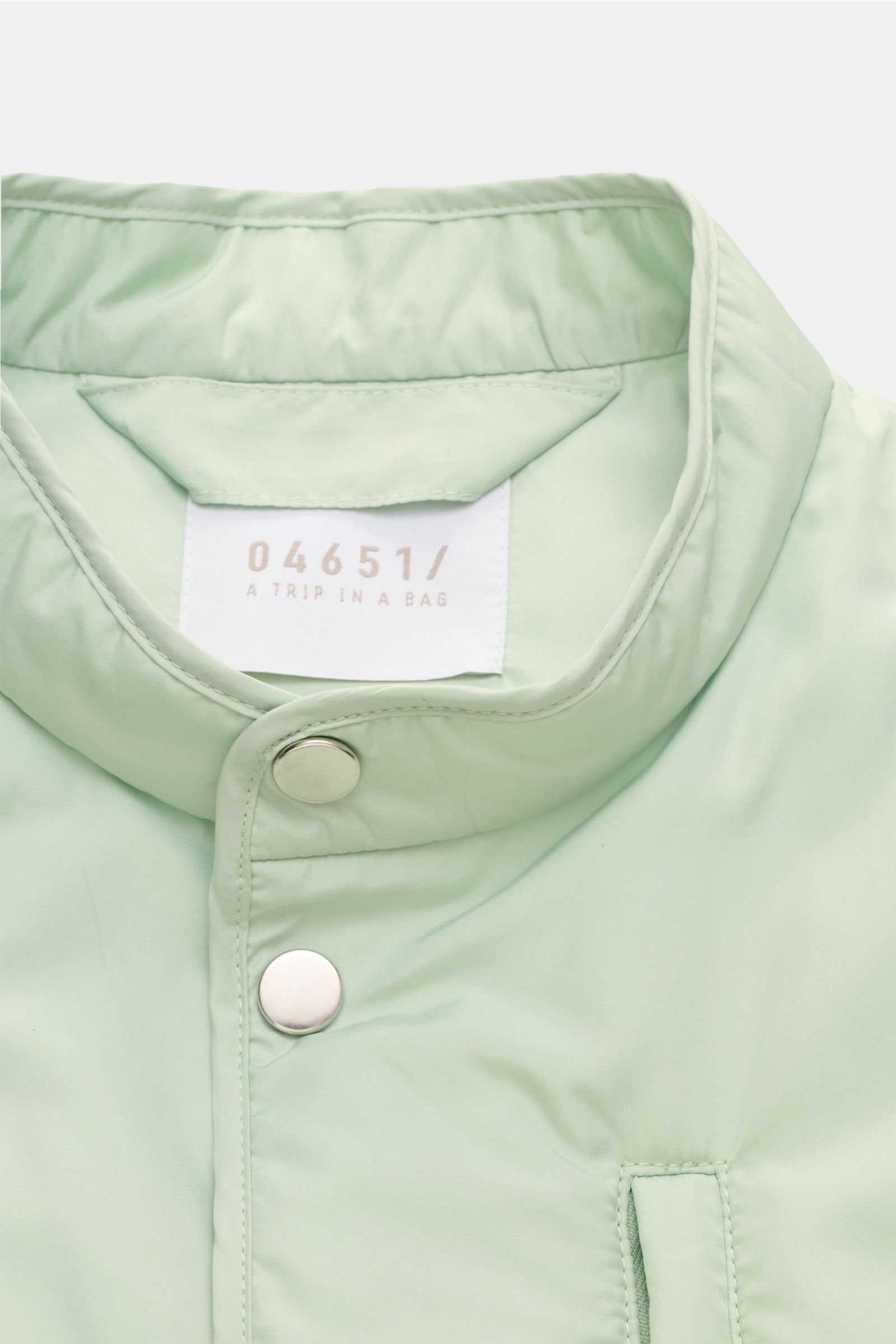 Nahaufnahme der pastellgrünen 04651/ A trip in a bag Outdoorweste 'Padded Nylon' mit Stehkragen und Fünf-Knopf-Leiste, glatter Microfaser.