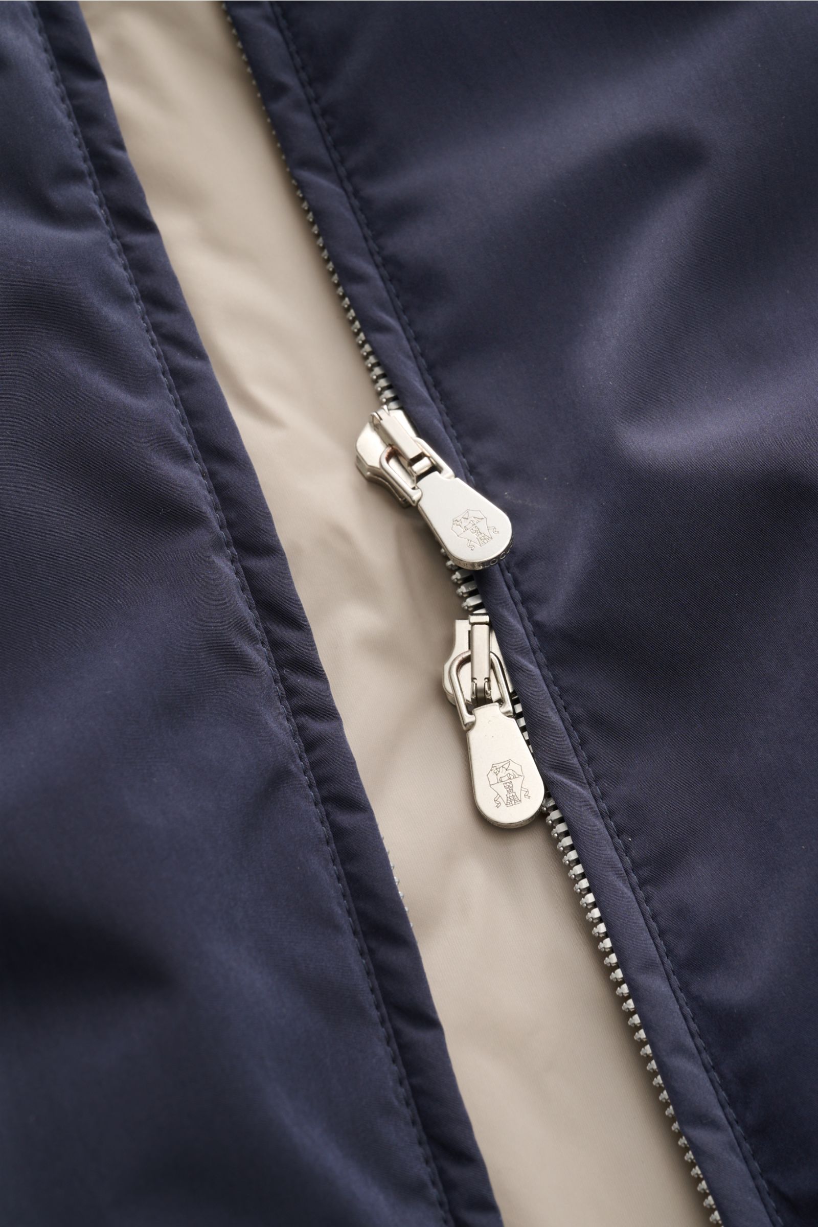 Nahaufnahme der zwei-Wege-Reißverschlüsse der navyfarbenen Brunello Cucinelli Outdoorweste, hochwertige Microfaser, weicher Griff, leichte Wattierung, Slim Fit, Stehkragen, Fronttaschen mit Druckknopf, geschmeidiges Futter, Rippbündchen, drei Innentaschen