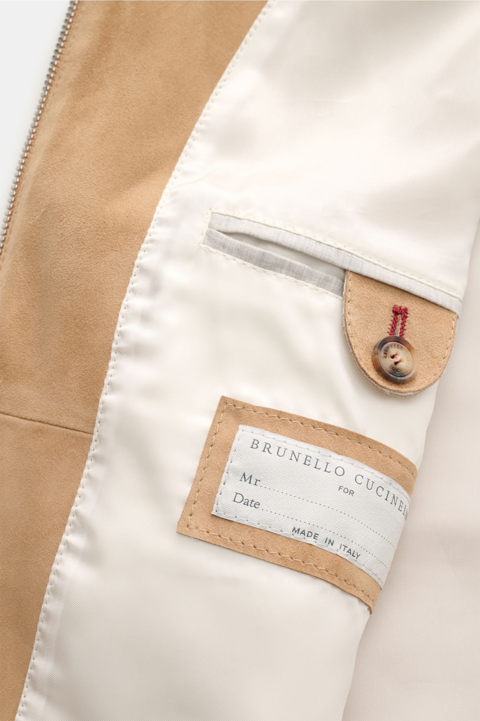 Close-up interior view of the Brunello Cucinelli Outdoorweste camel showcasing smooth beige velours leather, soft lining, button detail, and label. Edles Übergangs-Essential: Die Velourslederweste von BRUNELLO CUCINELLI verleiht Outdoor-Looks eine luxuriö
