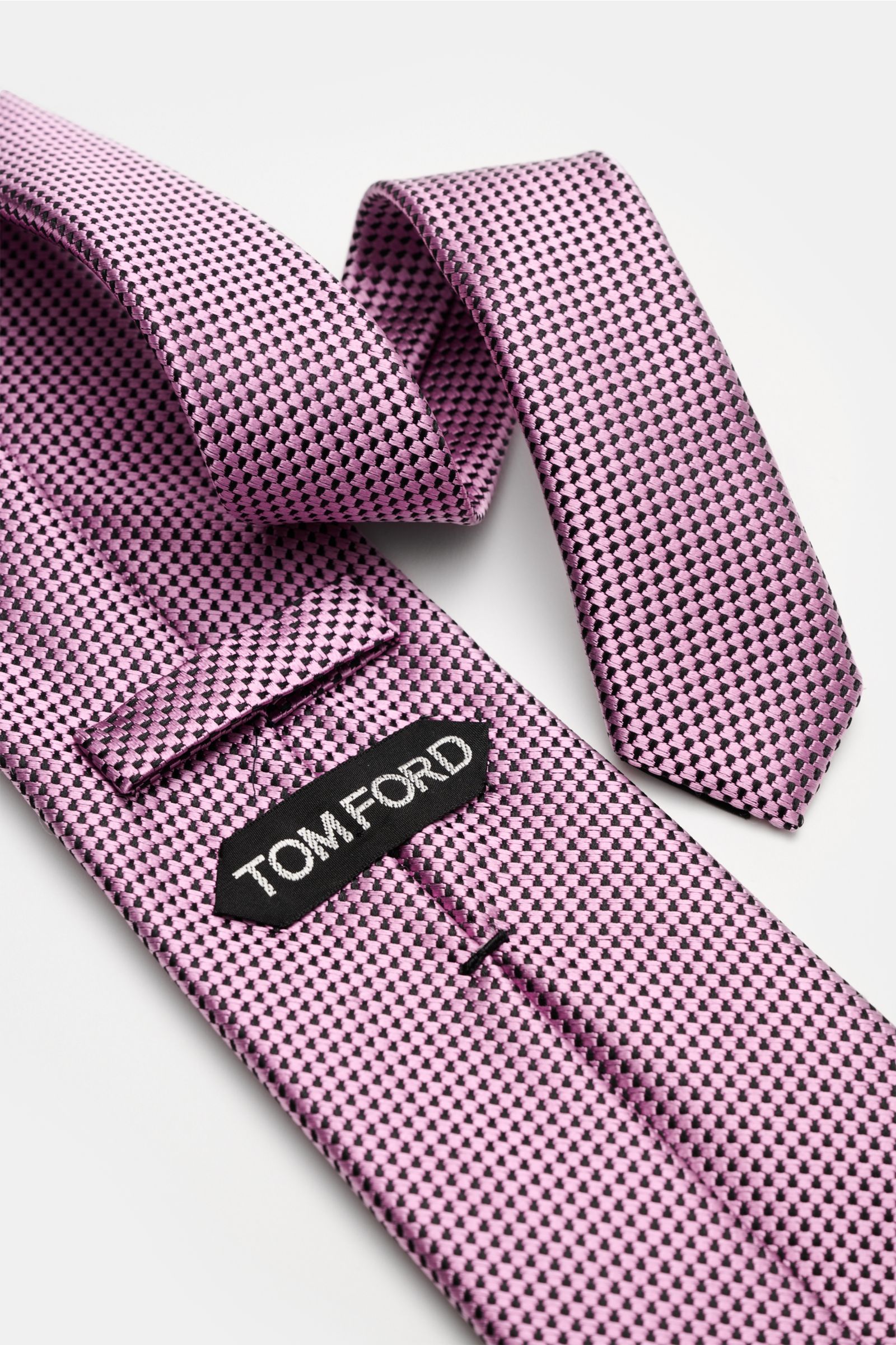 Close-up top view of Tom Ford Seidenkrawatte rosé/schwarz gemustert with fine graphic silk weave and subtle sheen.

Italienische Handwerkskunst: Dieser Krawatten-Klassiker von TOM FORD aus reiner Seide vereint zeitlose Eleganz mit einem feinen, grafisc