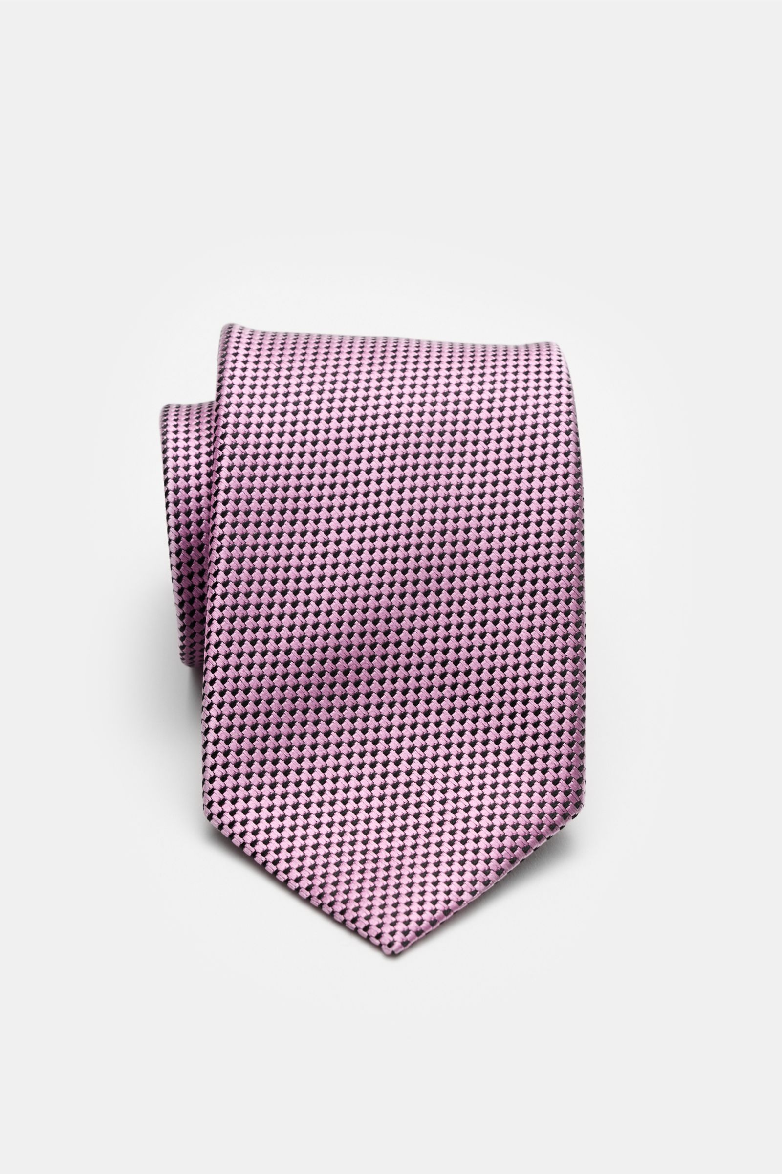 Front view of the folded Tom Ford Seidenkrawatte rosé/schwarz gemustert, a pure silk tie with a fine graphic weave and subtle sheen.

Description:  
Italienische Handwerkskunst: Dieser Krawatten-Klassiker von TOM FORD aus reiner Seide vereint zeitlose 
