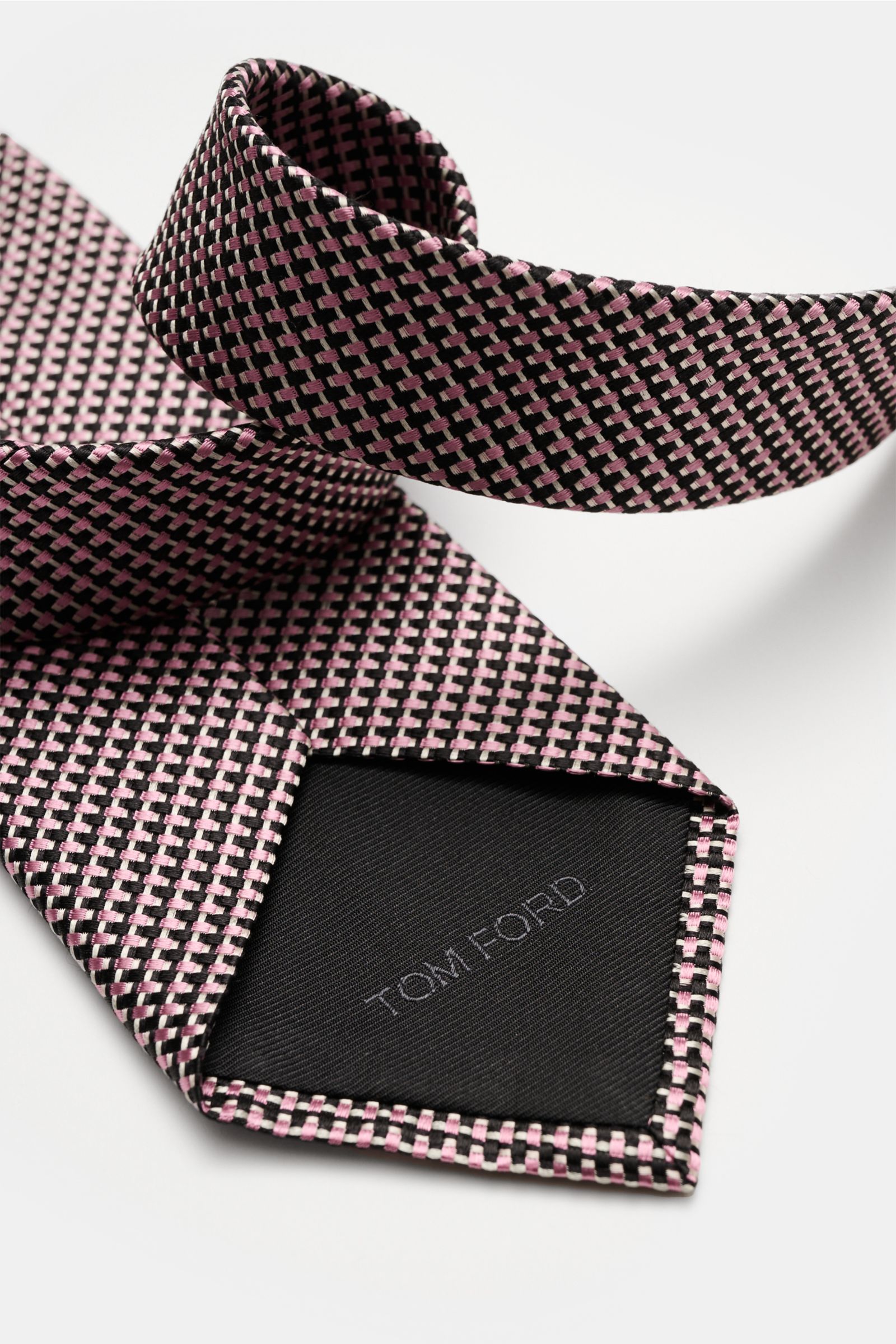 Close-up front view of Tom Ford Seidenkrawatte rosé/schwarz/grau gemustert with pink, black, and gray woven silk pattern, subtle sheen and branded lining.

Italienische Handwerkskunst: Dieser Krawatten-Klassiker von TOM FORD aus reiner Seide vereint ze