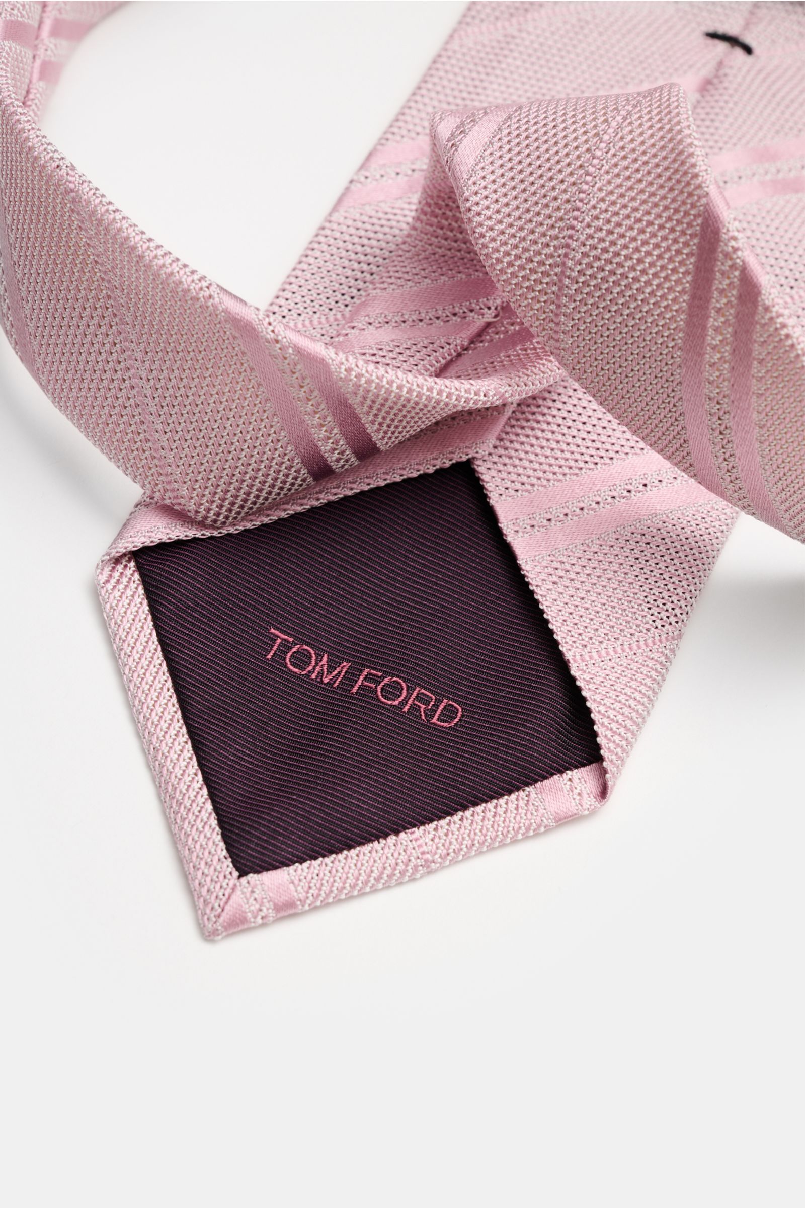 Close-up top view of Tom Ford Seidenkrawatte altrosa/weiß gestreift with fine silk weave, subtle shine, and branded lining.

Description: Italienische Handwerkskunst: Dieser Krawatten-Klassiker von TOM FORD aus reiner Seide vereint zeitlose Eleganz mit