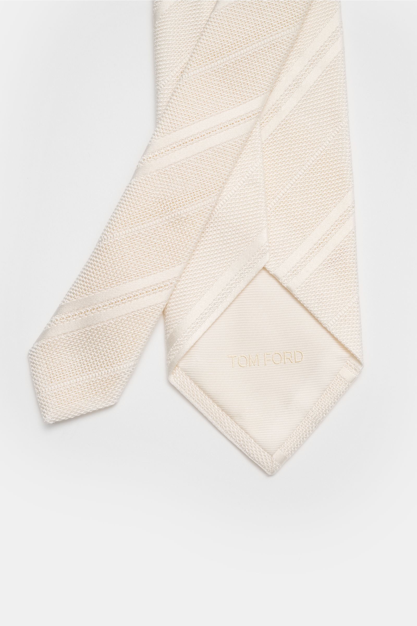 Close-up top-down view of Tom Ford Seidenkrawatte creme/weiß gestreift showing fine woven stripes, subtle sheen, and branded lining. 

Italienische Handwerkskunst: Dieser Krawatten-Klassiker von TOM FORD aus reiner Seide vereint zeitlose Eleganz mit ei