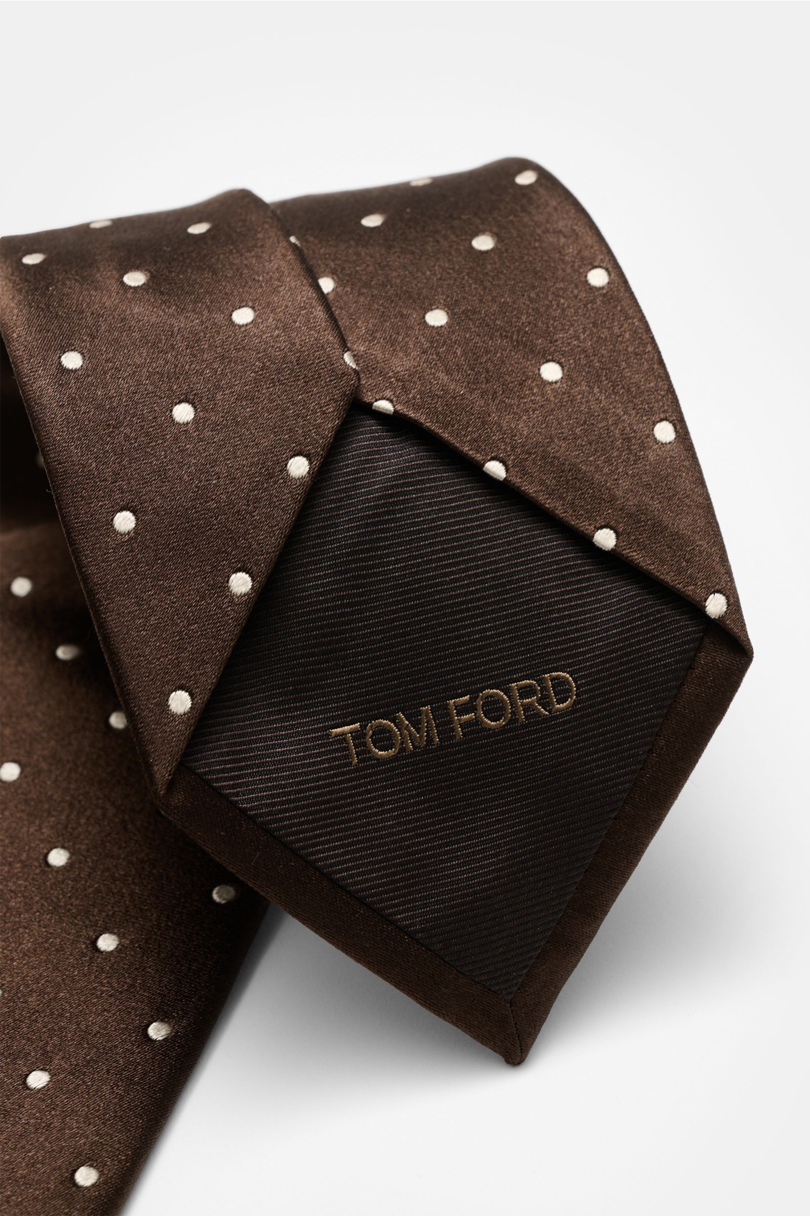 Alt tag (125 characters): Close-up front view of Tom Ford Seidenkrawatte dunkelbraun/creme gepunktet silk tie with subtle sheen and logo stitch.

Detailed description: 
Zeitloser Stil mit luxuriöser Note: Die Seidenkrawatte von TOM FORD überzeugt als e