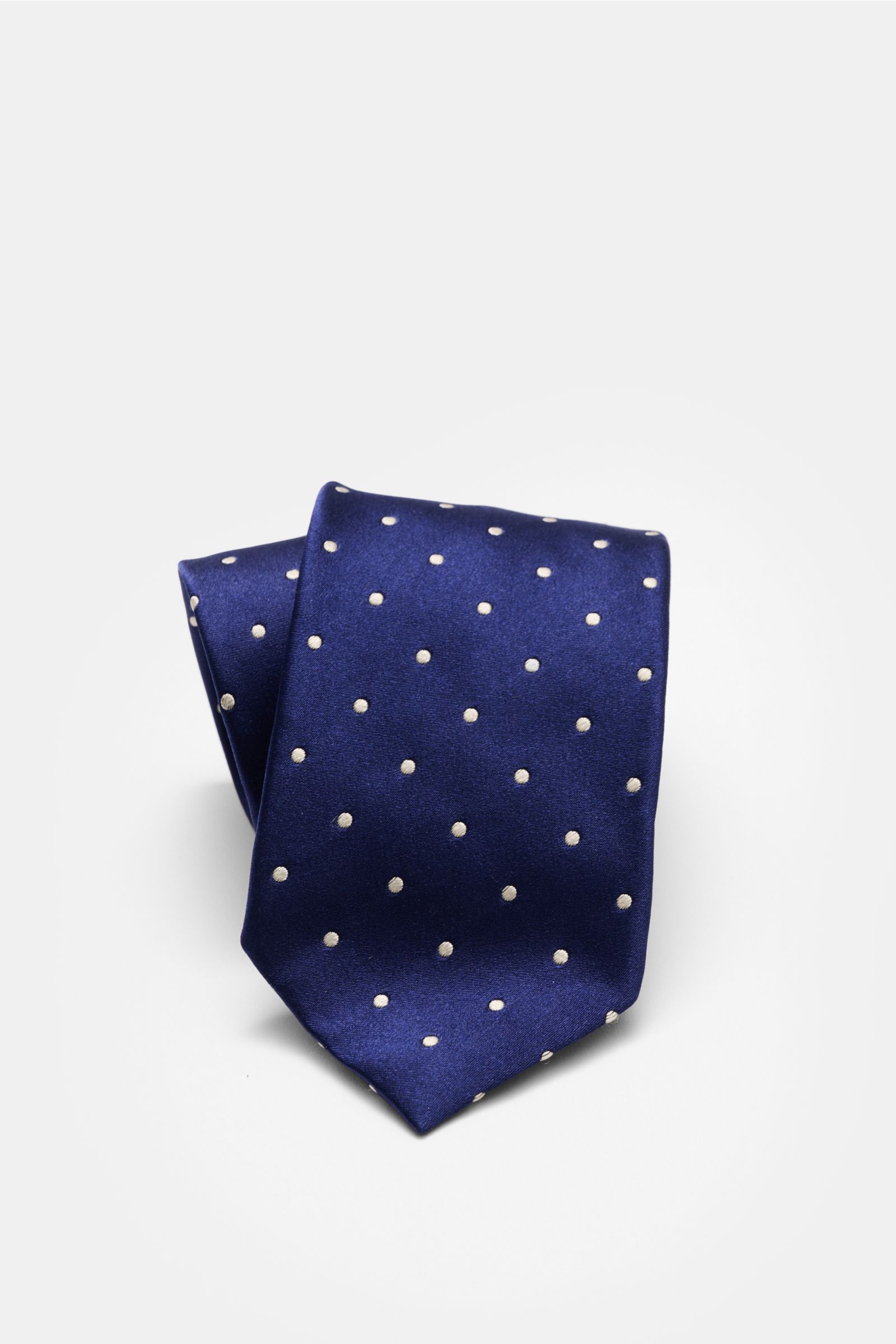 Close-up front view of the Tom Ford Seidenkrawatte dunkelblau/creme gepunktet silk tie with cream polka dots on dark blue, showing subtle sheen and folded tip.

Zeitloser Stil mit luxuriöser Note: Die Seidenkrawatte von TOM FORD überzeugt als elegantes