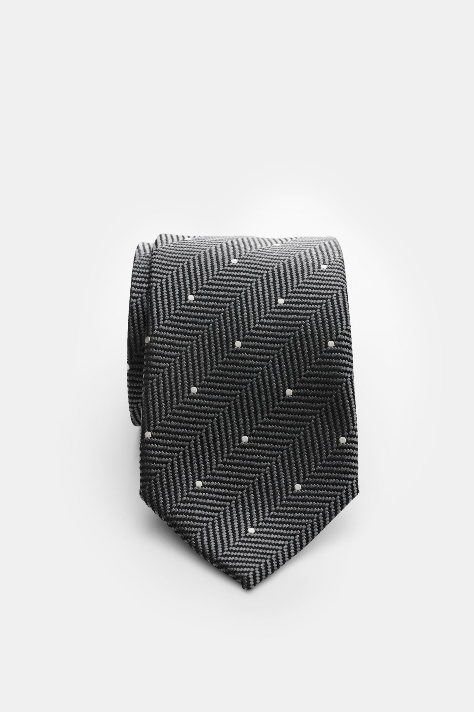 Tom Ford Seidenkrawatte dunkelgrau/schwarz/creme gemustert, Fischgrat mit Punkten, reine Seide, dezenter Glanz, Logo-Stitching, 8 cm breit, seitlich fotografiert.