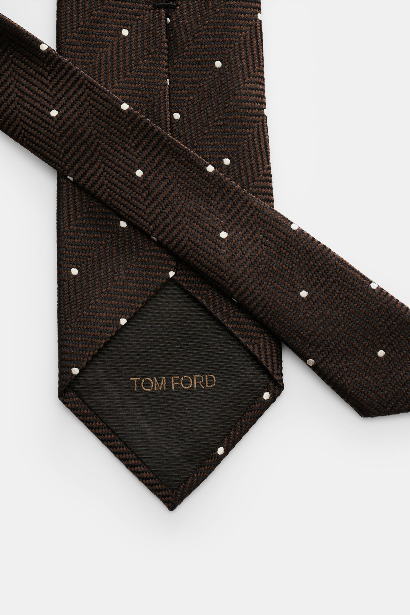 Tom Ford Seidenkrawatte dunkelbraun/schwarz/creme gemustert mit Fischgratmuster und Punkten, reine Seide, gebündelt seitlich fotografiert.