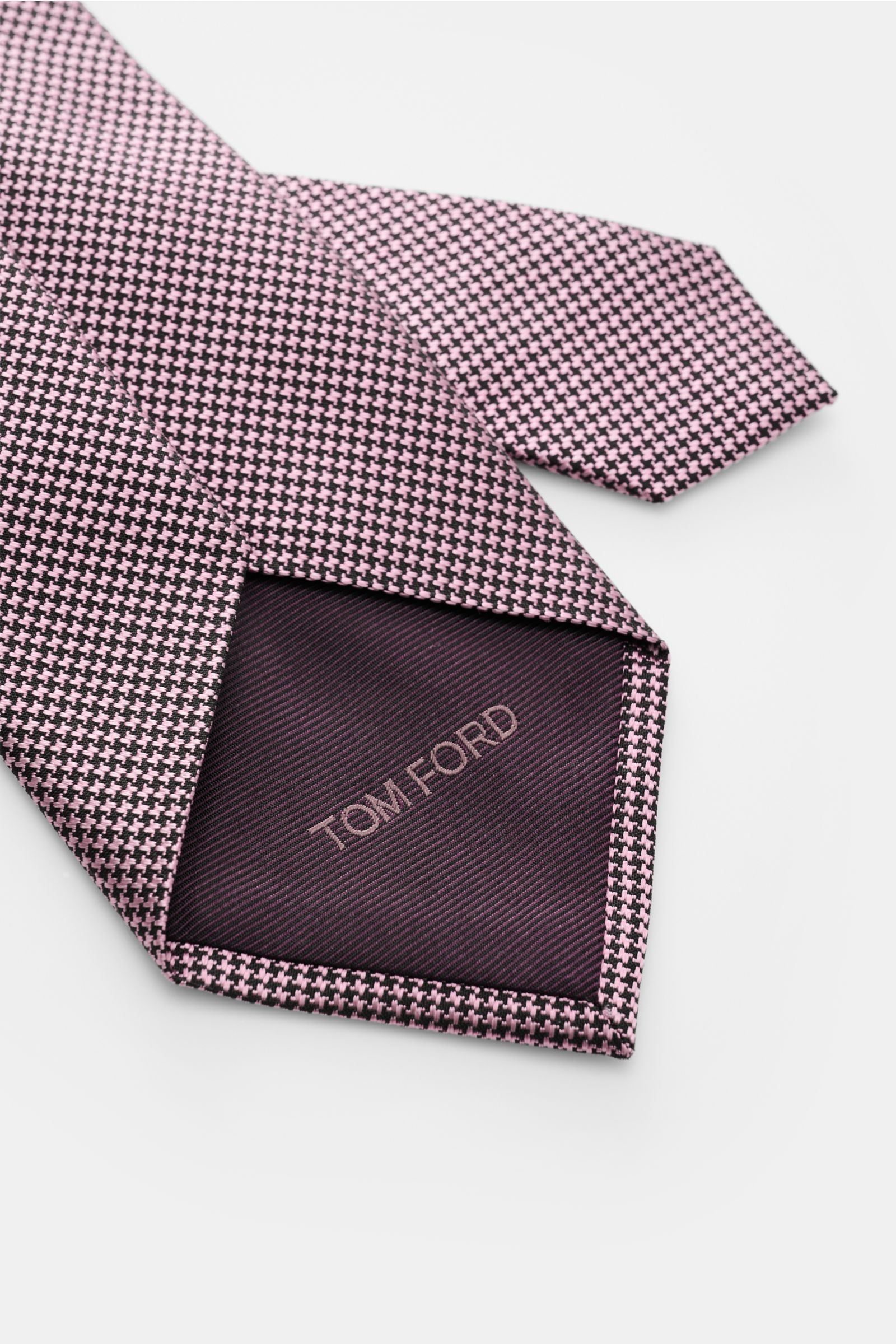 Tom Ford Seidenkrawatte rosé/schwarz gemustert, Hahnentritt, reine Seide mit dezentem Glanz, Logo-Stitching, Detailfoto von unten.