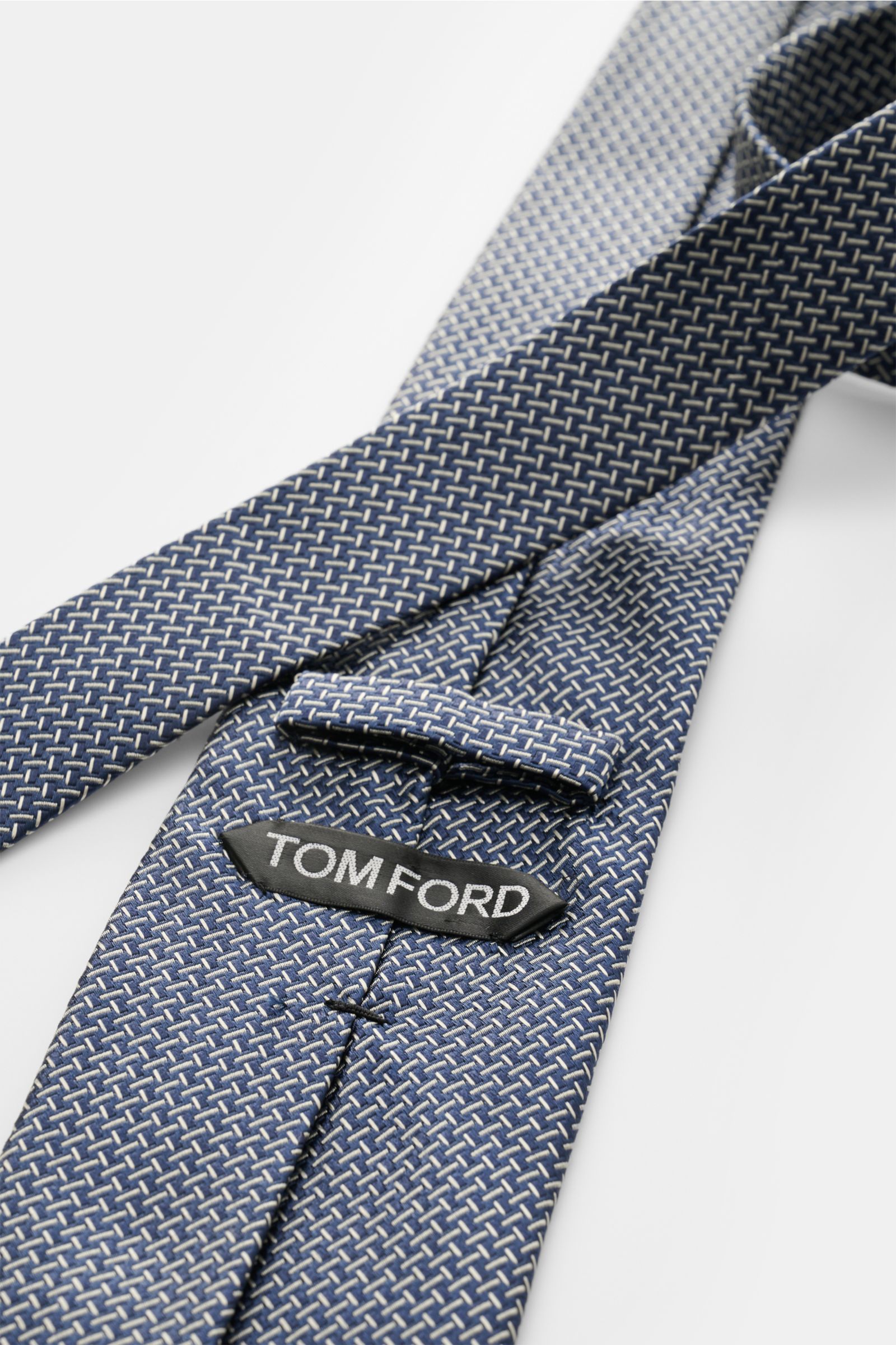 Tom Ford Seidenkrawatte navy/creme gemustert, aus reiner Seide mit dezentem Glanz, Logo-Stitching, Breite 8 cm, Nahaufnahme von oben.